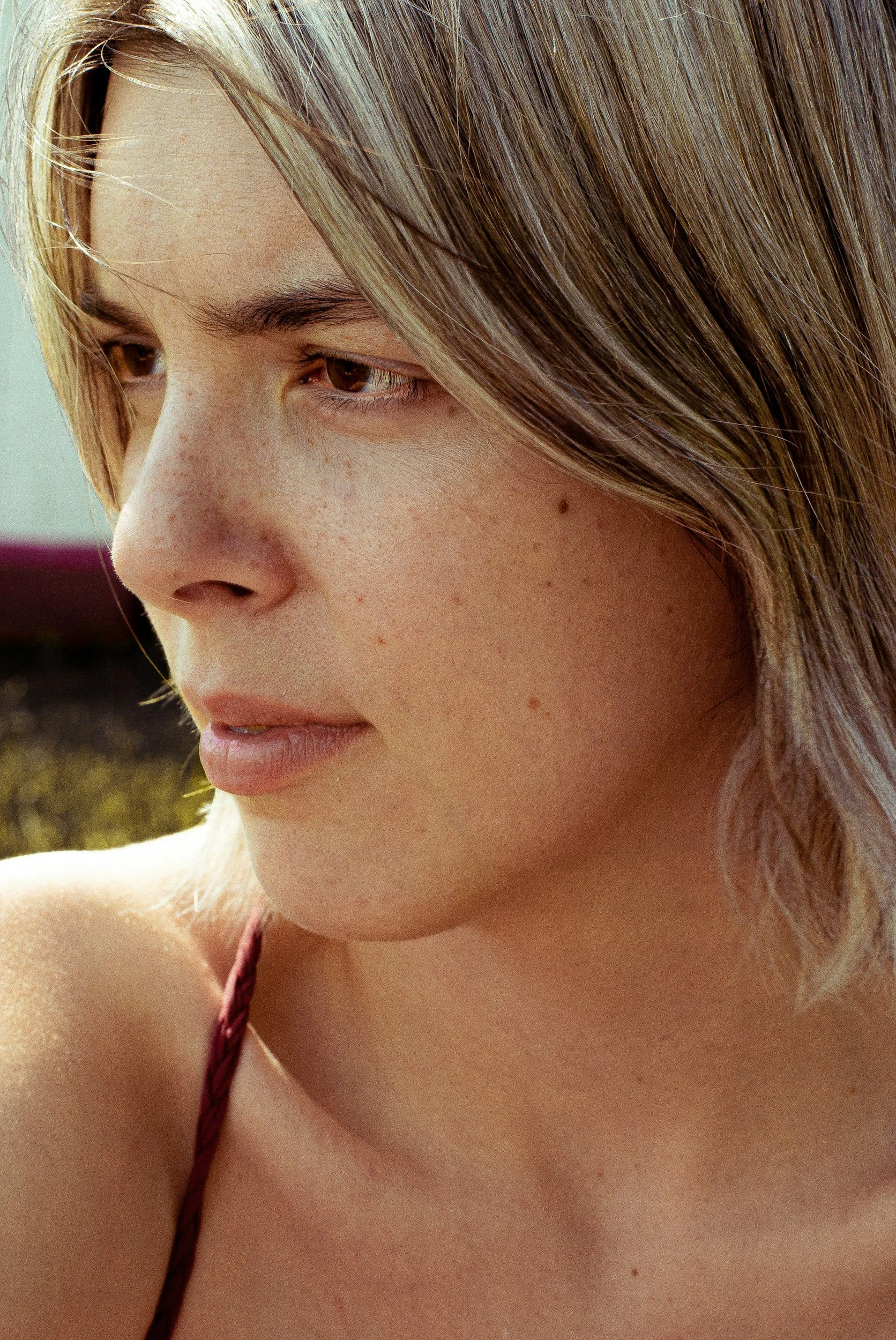 Close-up of a person with light brown hair and a thoughtful expression, looking to the left.