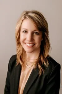 Professional woman smiling in a suit against a neutral background