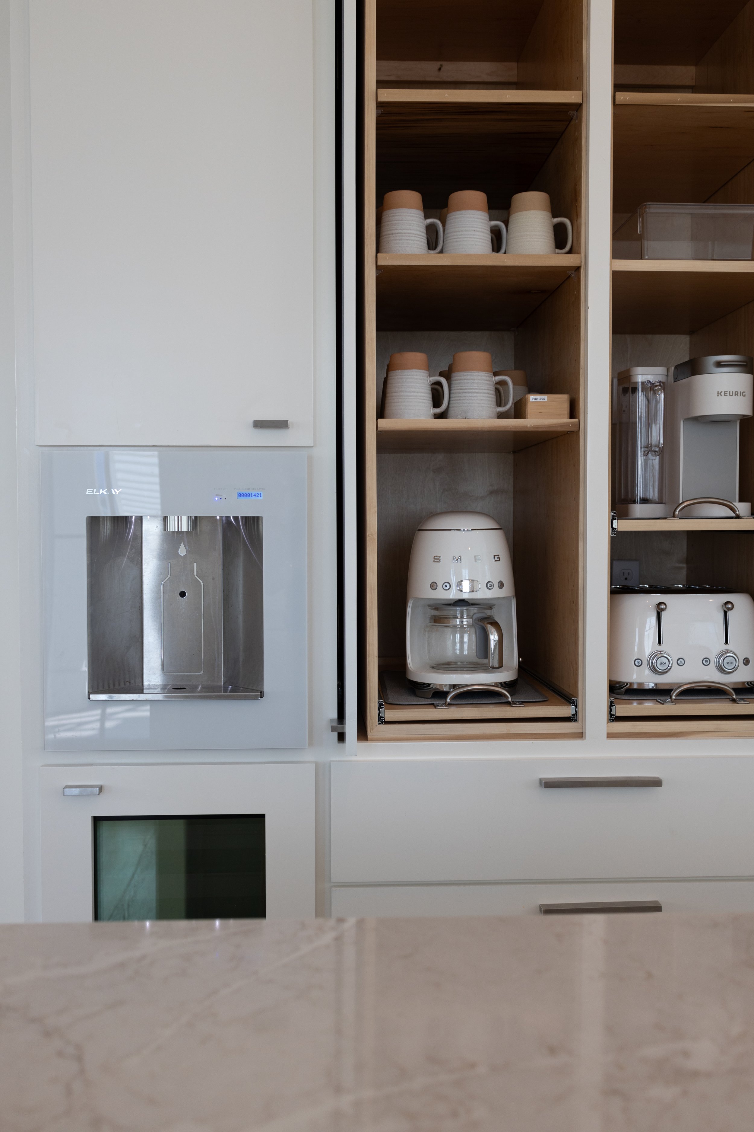 Coffee Bar with Sliding Hiding Retractable Cabinet Doors. Residential Water Filtration System. Minimalist White Kitchen Cabinetry. Marco Polo Lane Project, Cinnamon Shore North. Port Aransas, Texas - residential design by licensed architect Stefanie 