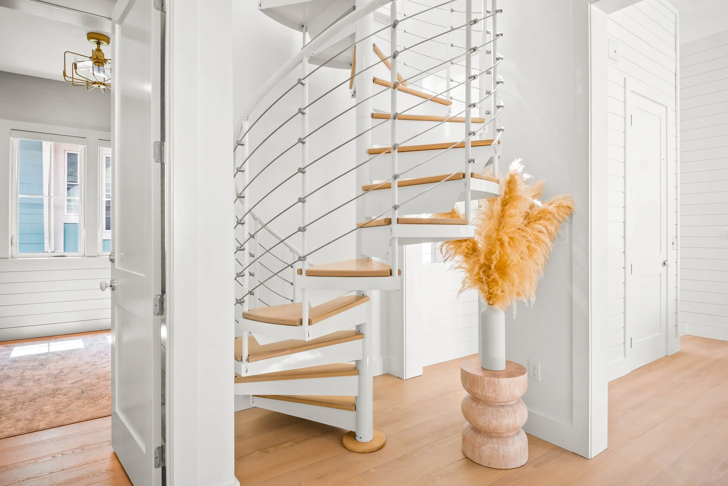 White Interior Spiral Staircase with Wooden Treads and Threaded Metal Rod Railing. Traditional Coastal House. Marco Polo Lane Project, Cinnamon Shore North. Port Aransas, Texas - residential design by licensed architect Stefanie Mustian, Board and Ba