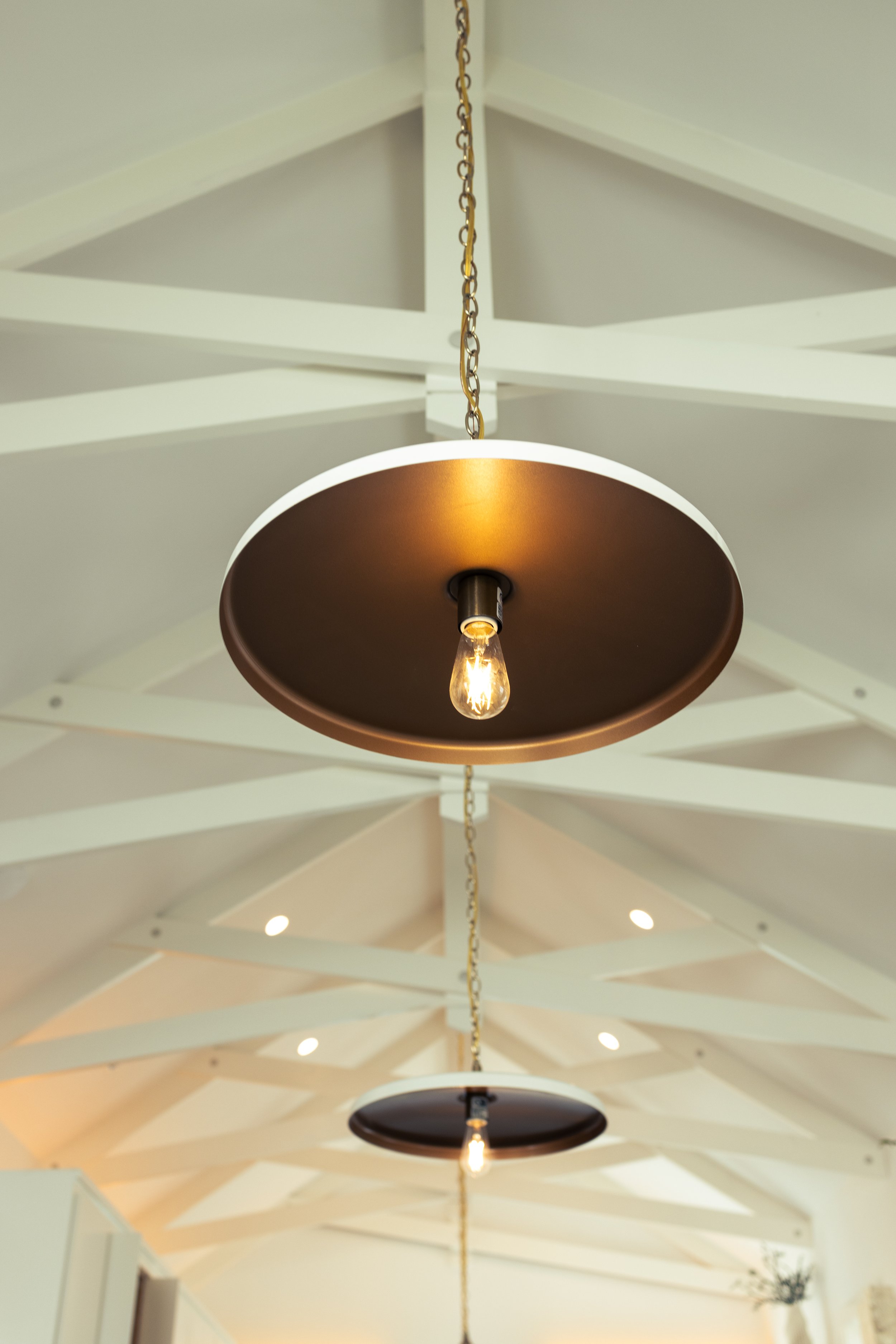 Close up of Exposed White Trusses and Traditional White and Brass Hanging Pendant Lights. Marco Polo Lane Project, Cinnamon Shore North. Port Aransas, Texas - residential design by licensed architect Stefanie Mustian, Board and Batten Architecture an