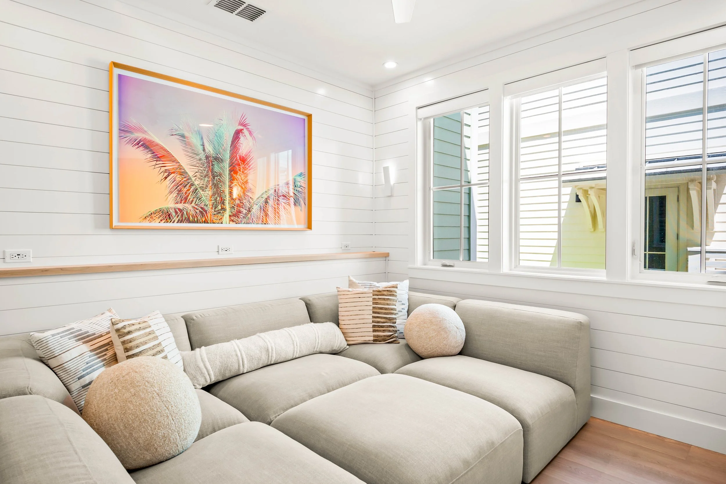 Media Room with Extra Large Lounging Couch and Technology Charging Ledge with Neon Coastal Art. Marco Polo Lane Project, Cinnamon Shore North. Port Aransas, Texas - residential design by licensed architect Stefanie Mustian, Board and Batten Architect