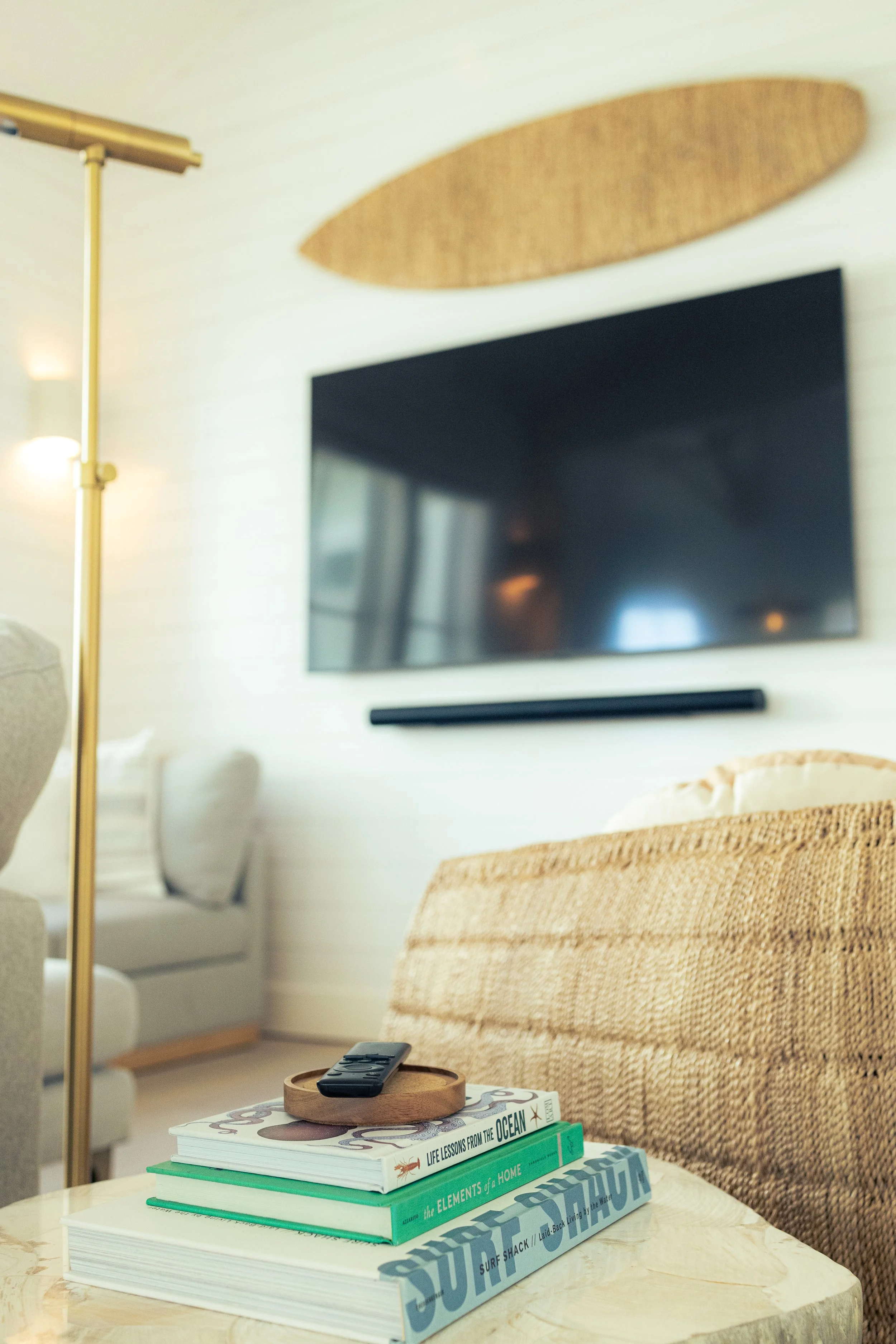 Rattan Chair and Rattan Surfboard Art with TV in Modern Coastal Home. Marco Polo Lane Project, Cinnamon Shore North. Port Aransas, Texas - residential design by licensed architect Stefanie Mustian, Board and Batten Architecture and Design.