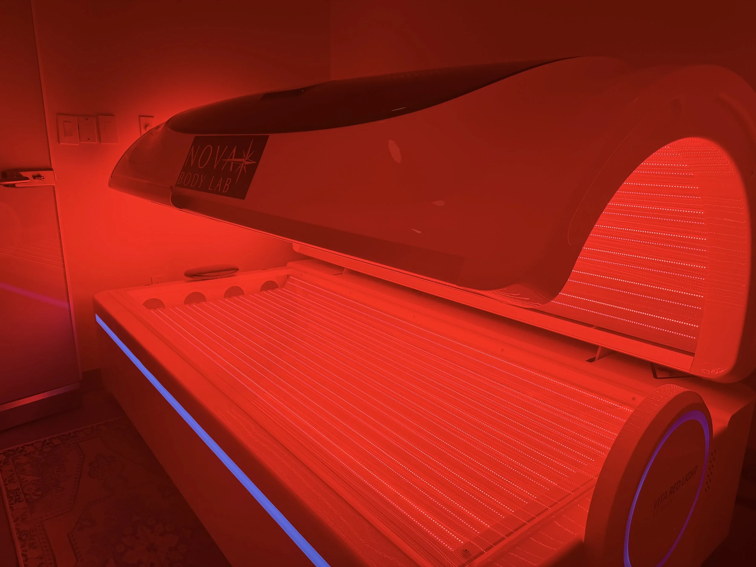 Close-up of a pink tanning bed with illuminated fluorescent lights.