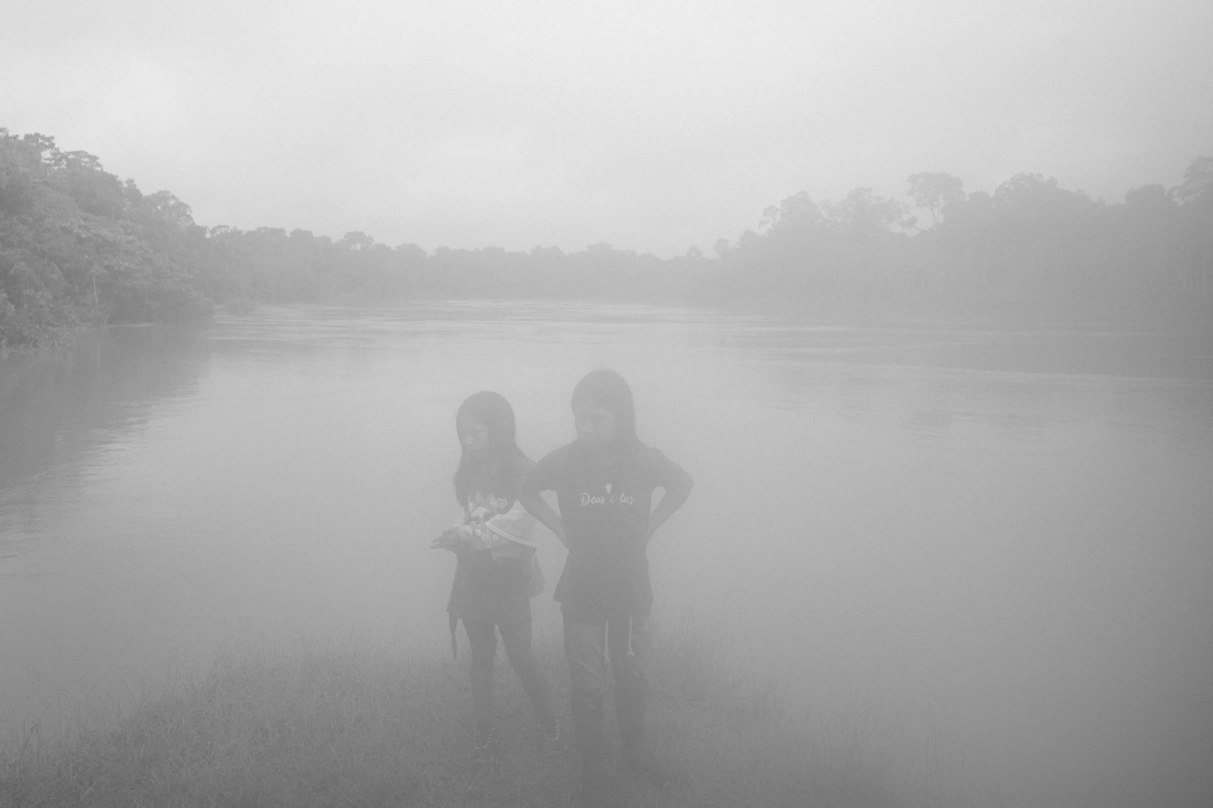 Two young Mayoruna girls are seen early in the morning on the Curuçá River, inside the Vale do Javari Indigenous Territory, waiting to be seen by a team of doctors and dentists visiting their village to provide medical care to the community.