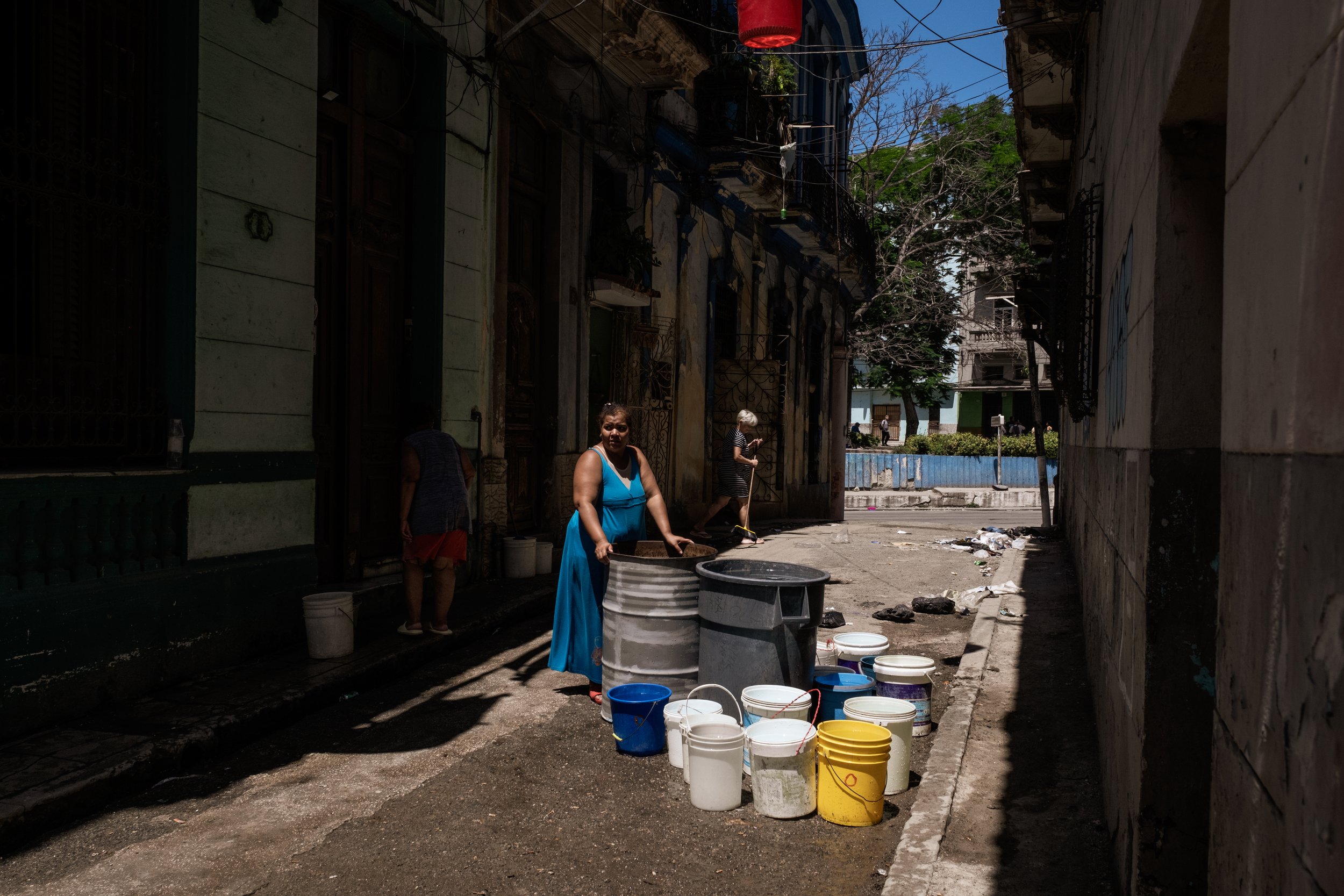 A woman fills water containers that are then hoisted up to apartments in the building using ropes. The water has been delivered by a tanker truck, a service that usually arrives no more than twice a week. 