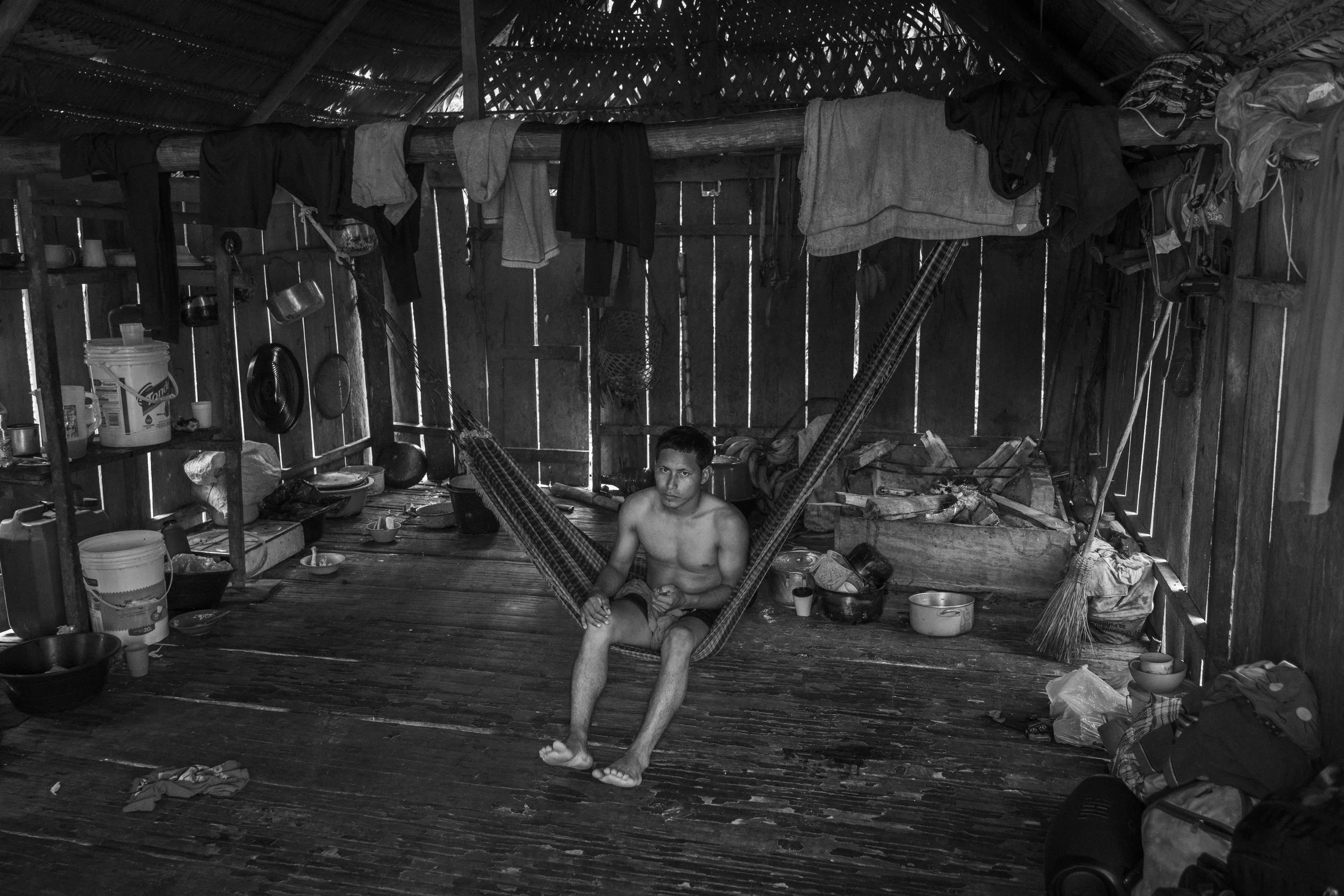 A young Mayoruna man inside his home in Flores village, on the Curuçá River, within the Vale do Javari Indigenous Territory, Brazil.