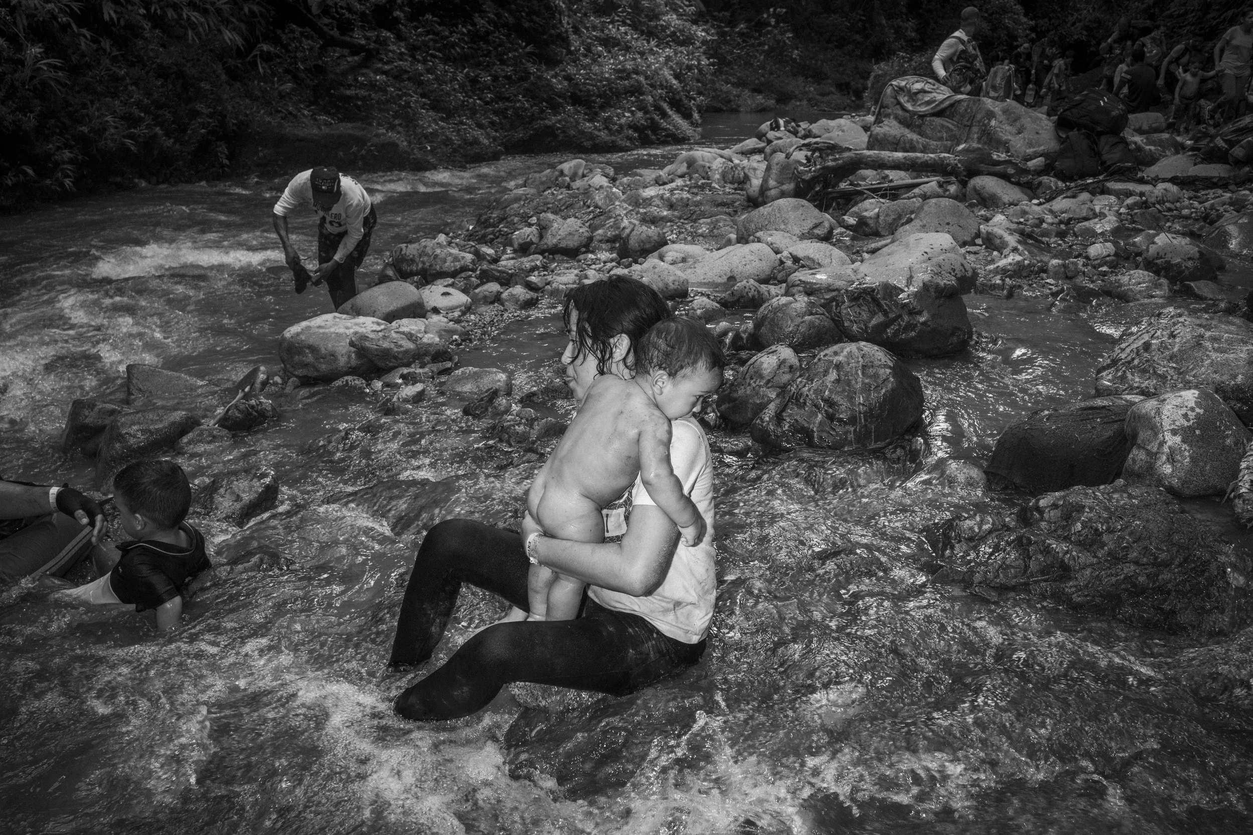 Lina Arias bathes her six-month-old son, Simón, in a river after trekking for several hours through the Darién Gap, navigating muddy terrain and river crossings.