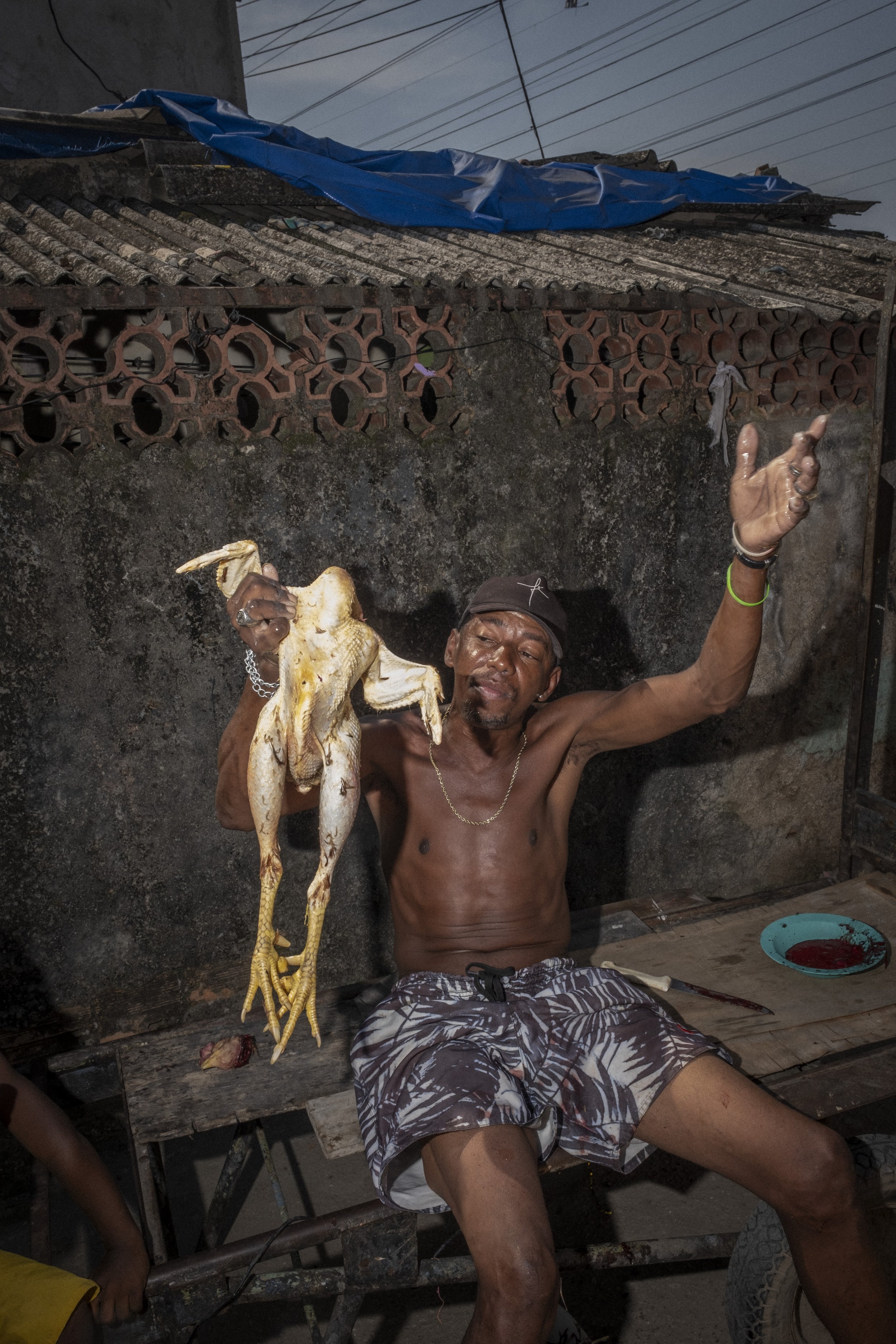 DUQUE DE CAXIAS, BRASIL — 4 DE MAIO DE 2023: Um homem brinca enquanto segura uma galinha antes de cozinhá-la na favela de Jardim Gramacho, em Duque de Caxias, região metropolitana do Rio de Janeiro.

DUQUE DE CAXIAS, BRAZIL — MAY 4, 2023: A man jokes
