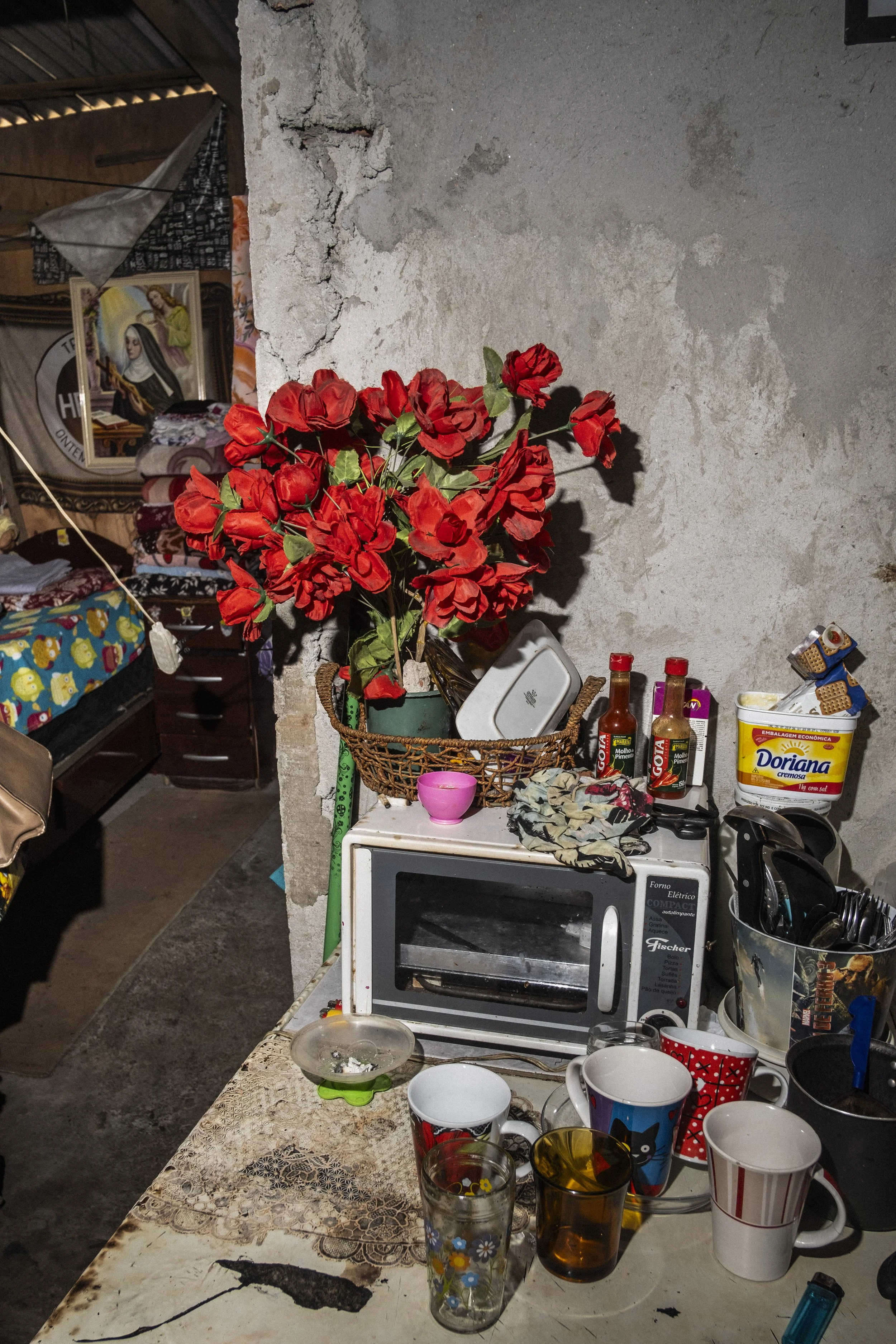 Flores artificiais decoram um micro-ondas dentro de uma casa simples no Jardim Peri Alto, em São Paulo.