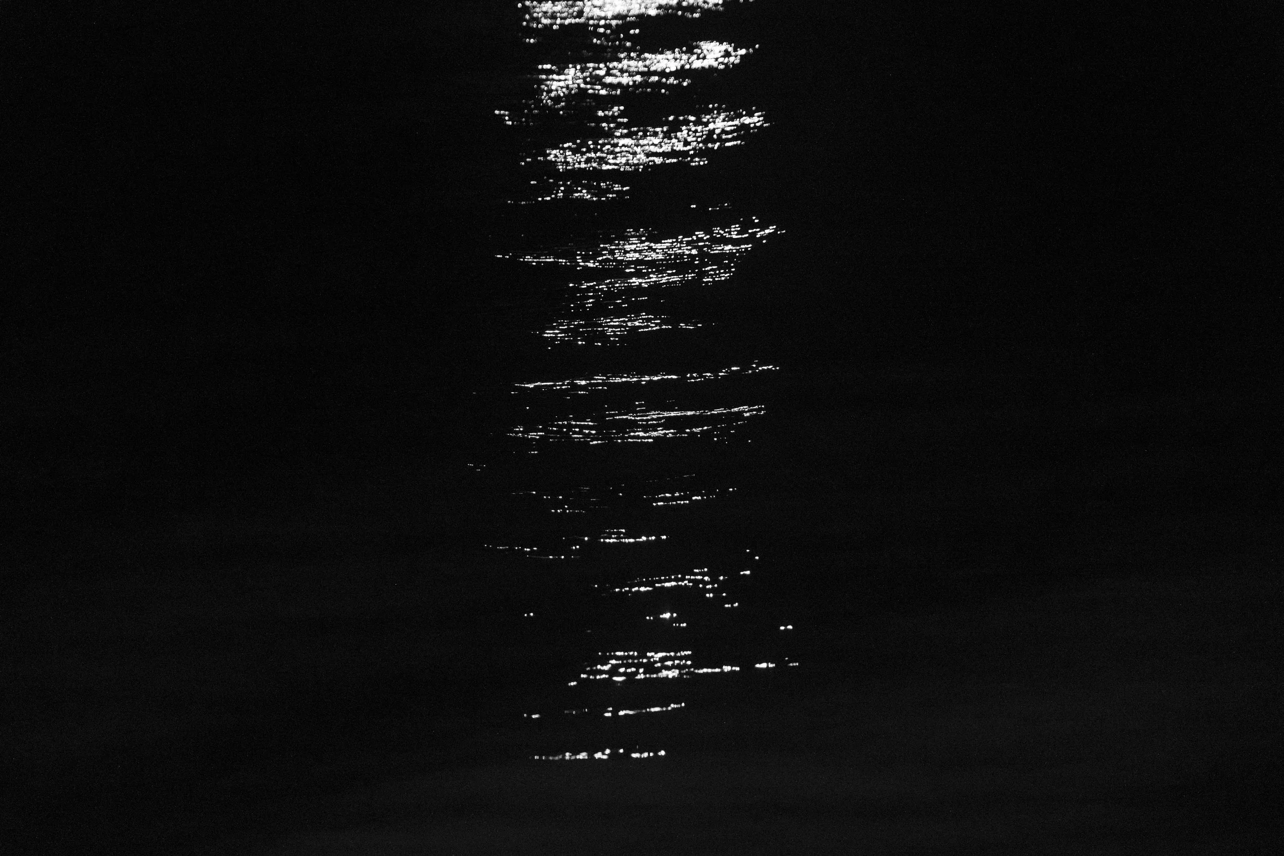 The reflection of lights from a commercial boat shimmers on the waves of the Solimões River as the vessel travels at night from Tabatinga toward Manaus, near the community of Capacete.