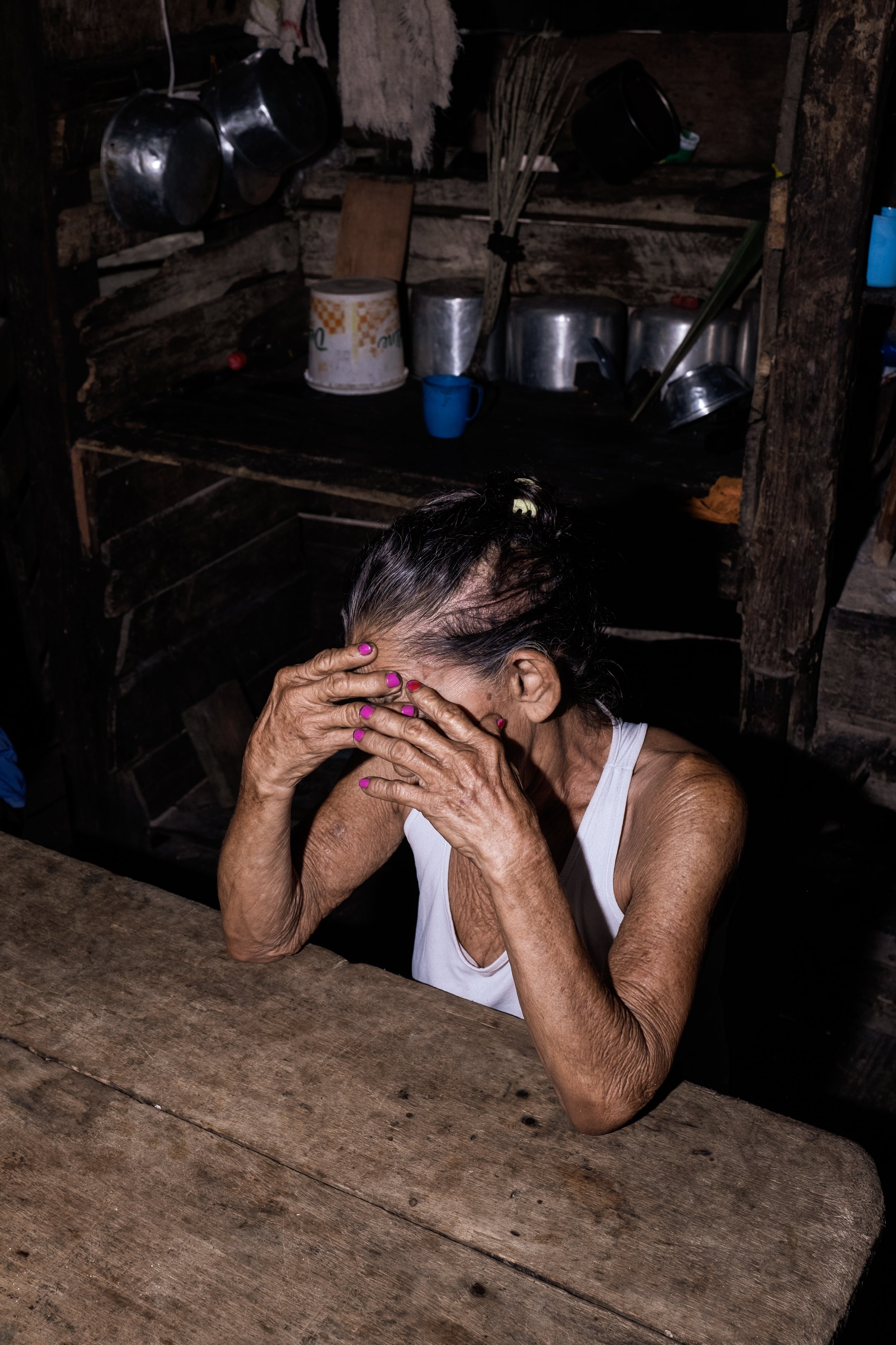 Maria Leal de Souza (81) é retratada em um momento de aflição dentro de sua casa sobre palafitas na comunidade ribeirinha de Santa Ana, em Melgaço, no estado do Pará — o município com o menor índice de desenvolvimento socioeconômico do Brasil. Sem ac