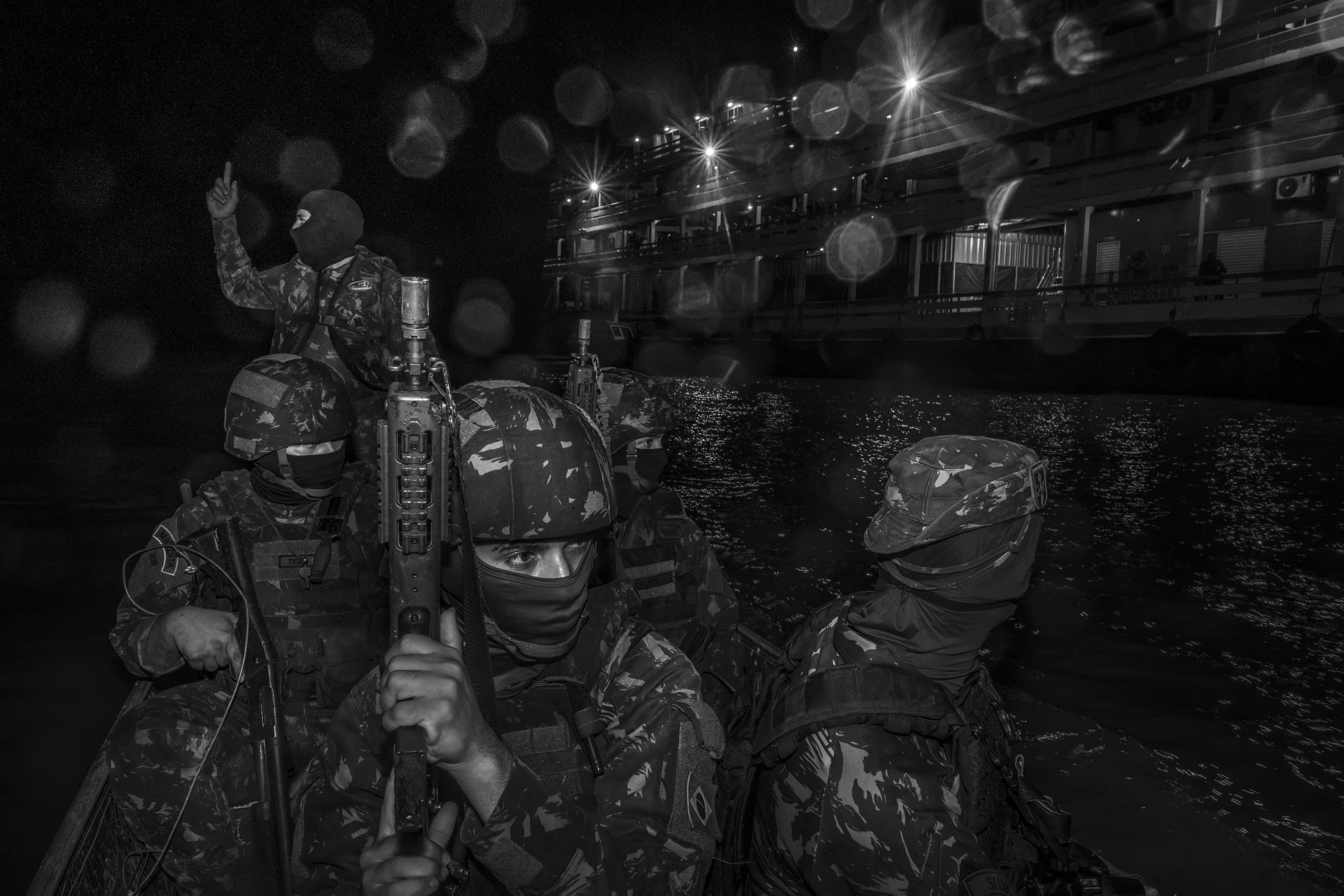 A squad of Brazilian Army soldiers approaches a commercial boat to conduct a search near the community of Capacete. The vessel, carrying passengers, equipment and supplies, travels at night along the Solimões River from Tabatinga toward Manaus as it 