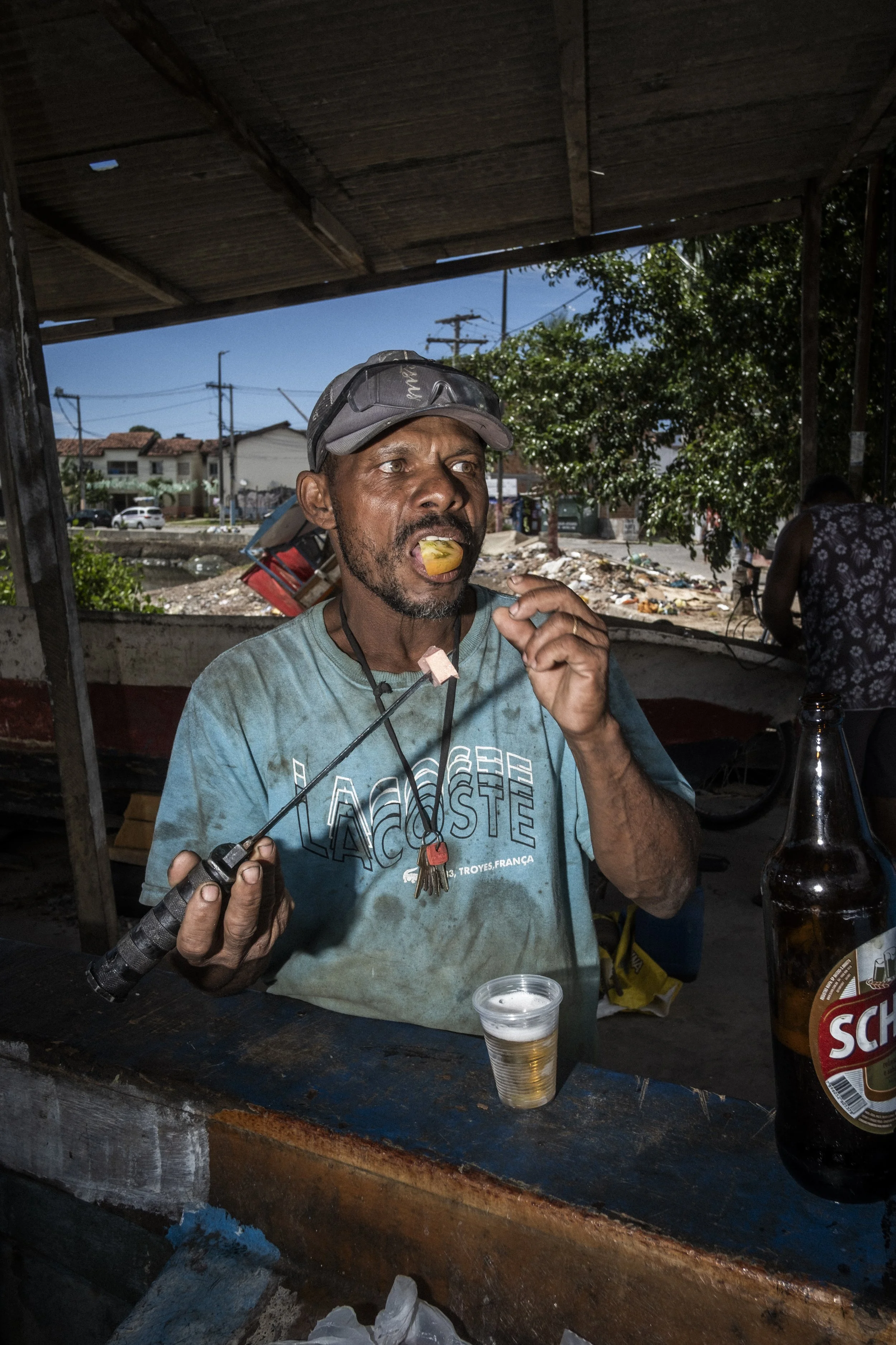 SALVADOR DE BAHIA, BRAZIL - FEBRUARY 01, 2023: Um pescador toma café da manhã em Salvador, Bahia, com limão, cerveja e mortadela.

SALVADOR DE BAHIA, BRAZIL - FEBRUARY 01, 2023: A fisherman has breakfast in Salvador, Bahia, with lime, beer, and morta