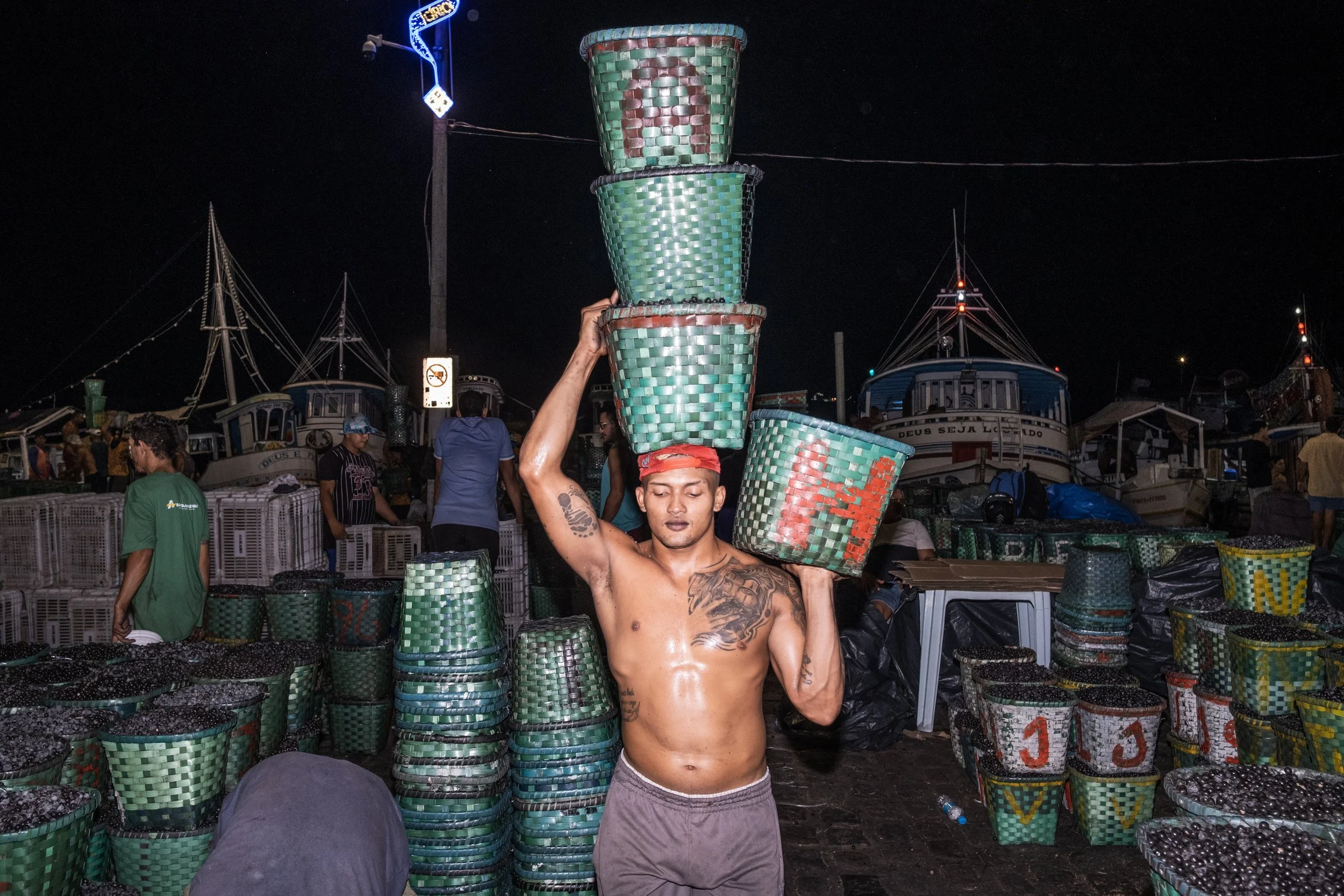 Um estivador descarrega cestos de açaí provenientes das ilhas ao redor de Belém, nas proximidades do mercado Ver-o-Peso, no Pará.