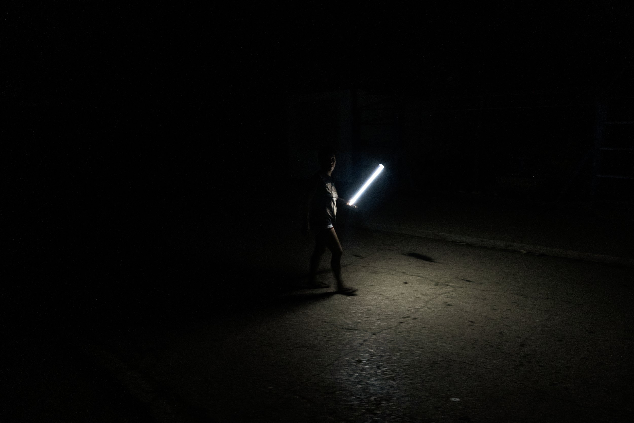 A woman uses a neon light to walk at night in Alamar, a large residential district in eastern Havana, during a blackout. 