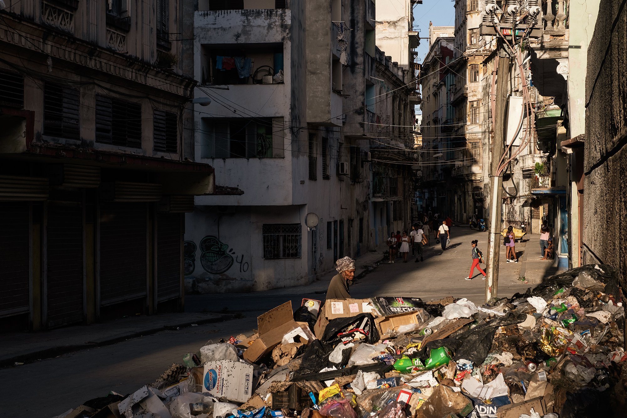 A woman searches for food and other items among garbage left on a street in Havana.