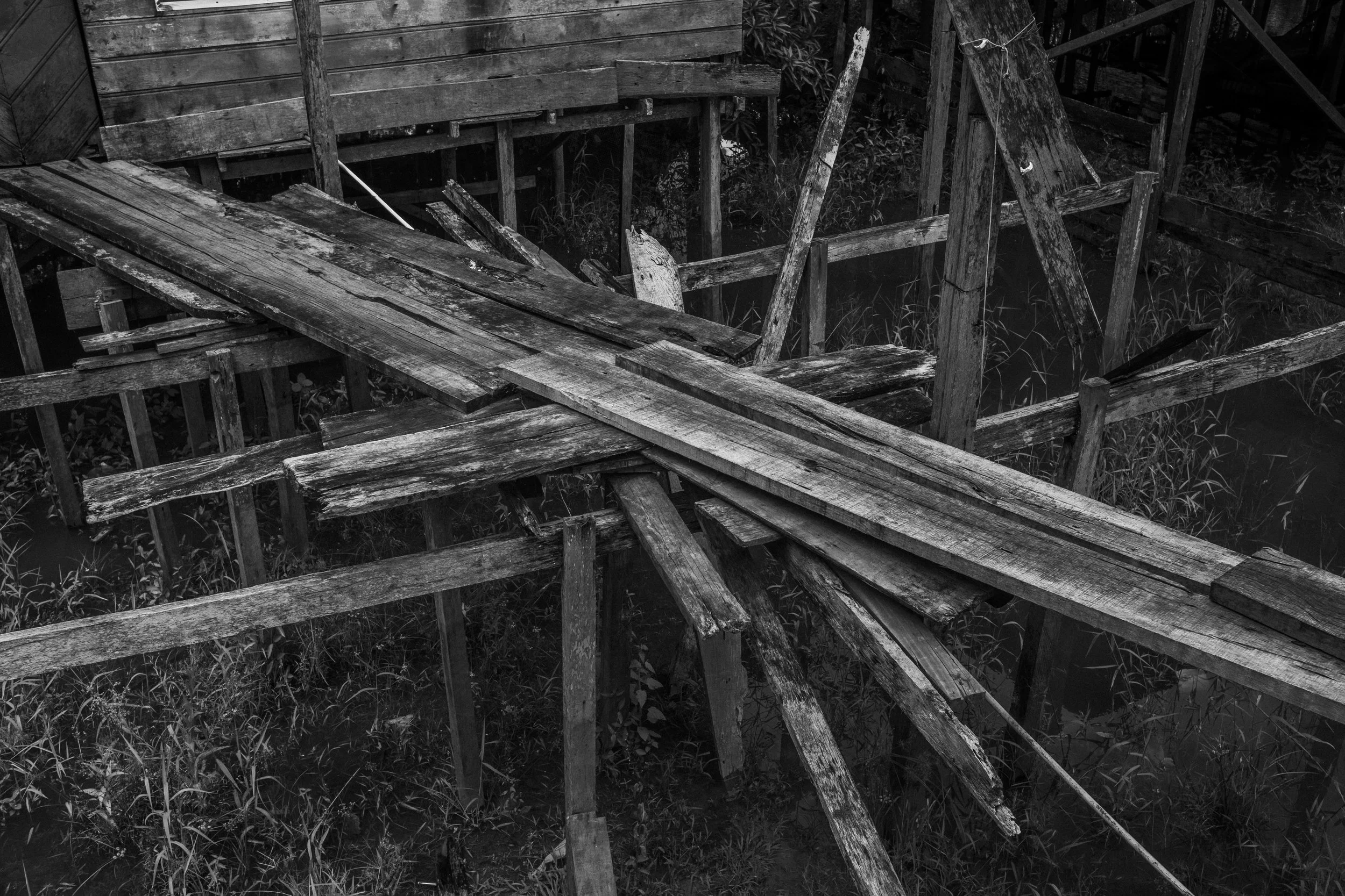 A damaged wooden walkway runs through the stilt houses of Islandia, a riverine town on the Peruvian side of the Javari River built entirely above the water. The community serves as one of the main gateways to the Vale do Javari Indigenous Territory.