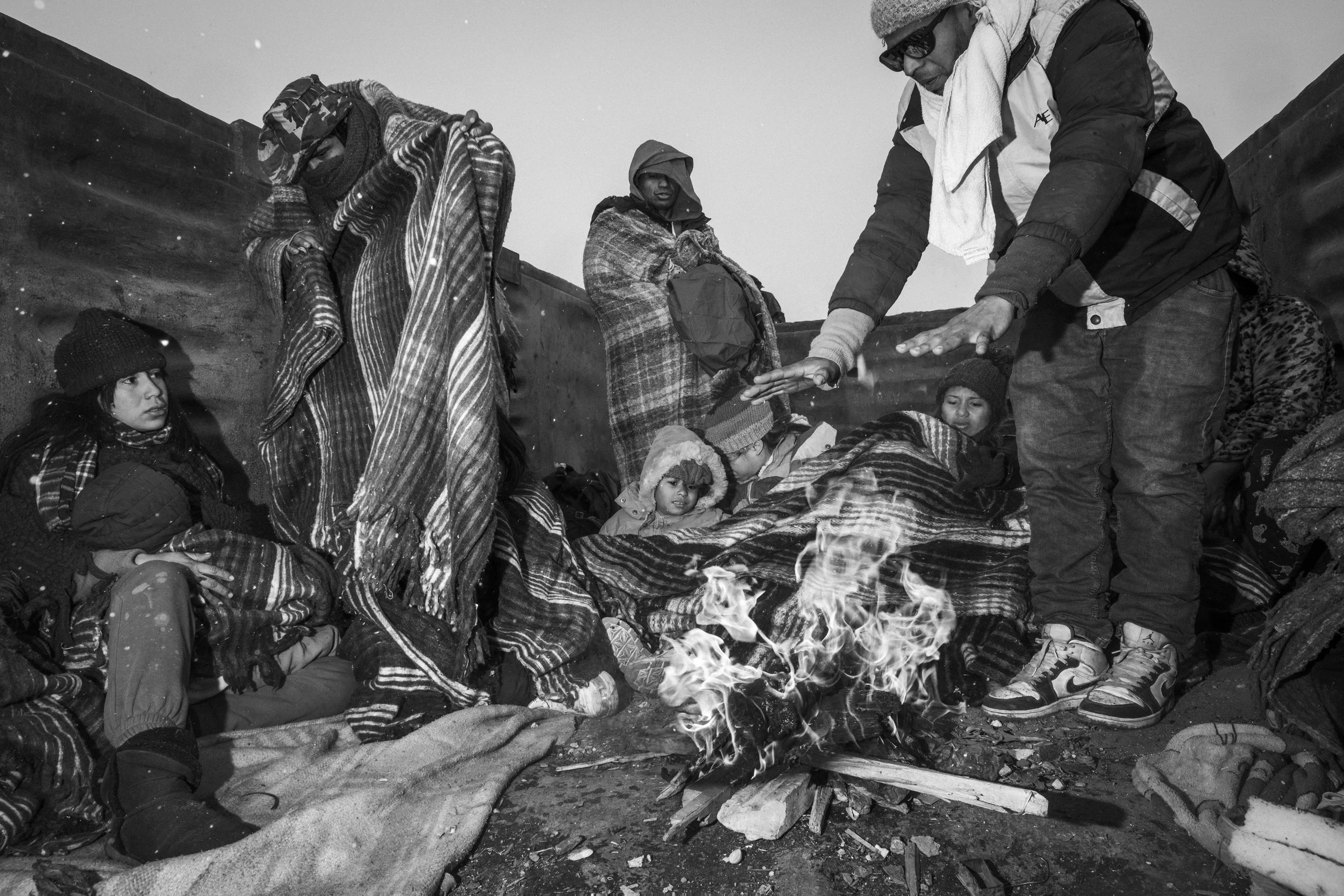 Cesar Atencio drapes a blanket over Lina Arias and their sons, trying to keep them warm.