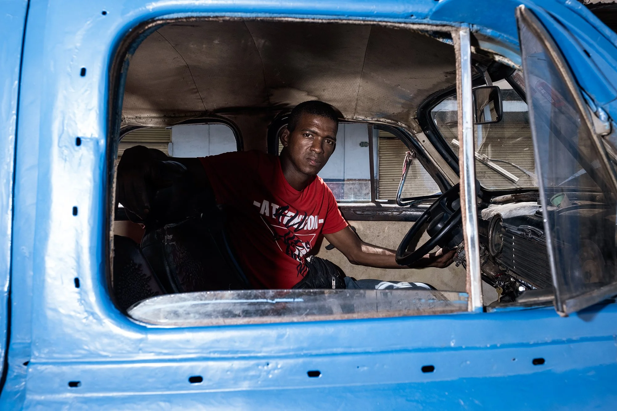 A young man inside his broken car. 