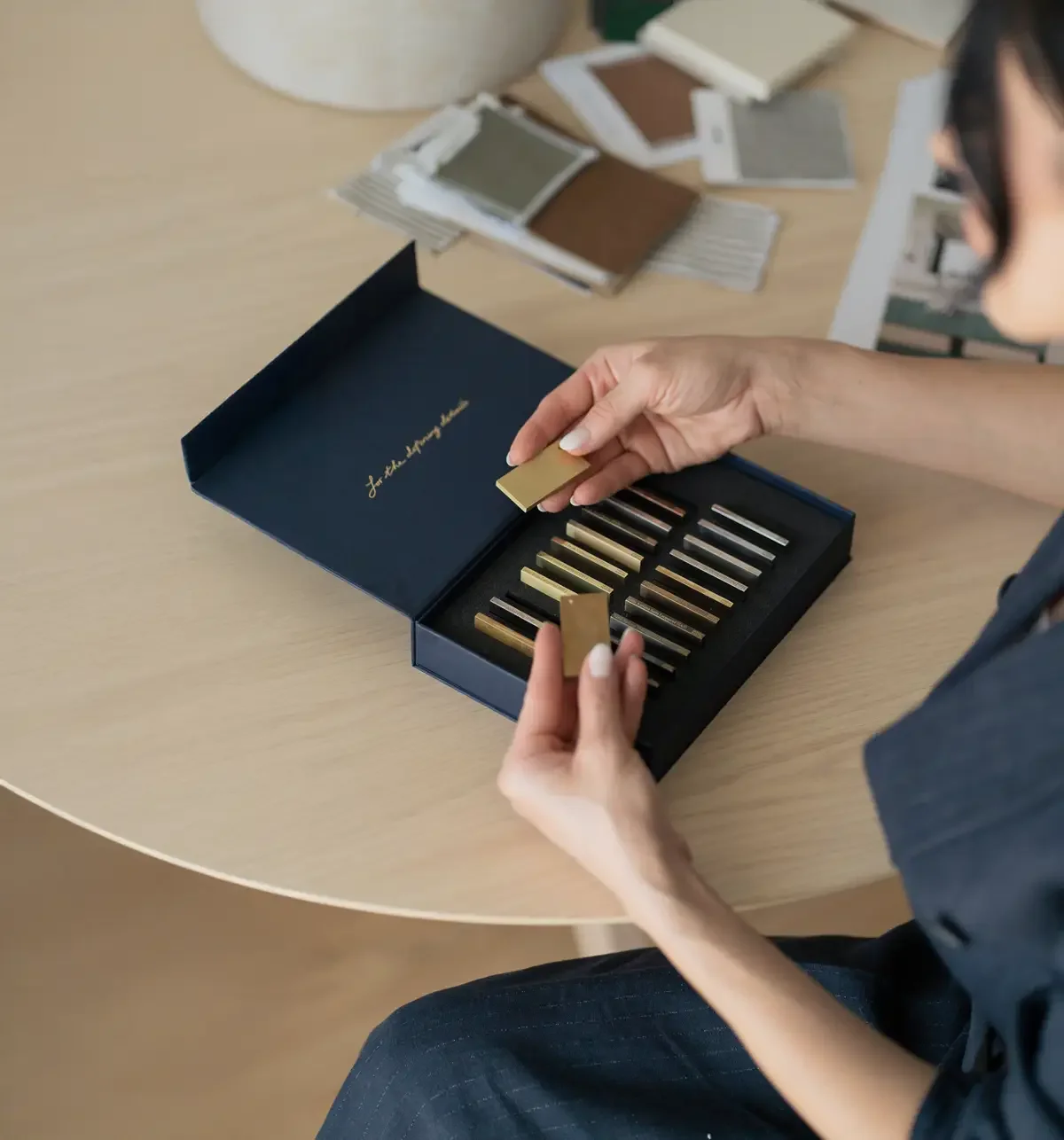 Madalina Aris opening an Armac Martin presentation box with metallic finish samples on display.