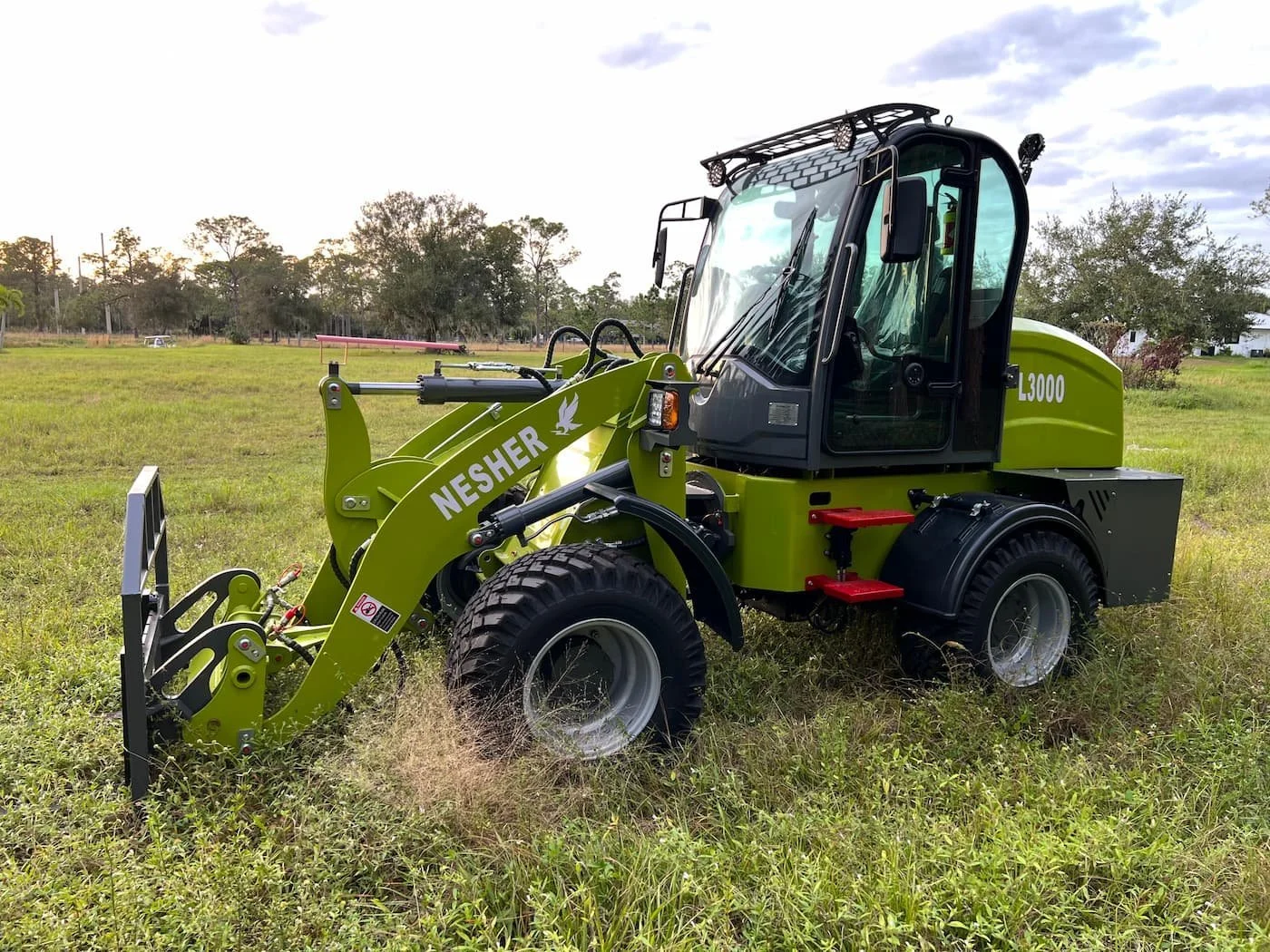 Green Nesher L3000 front loader construction vehicle on grassy field during daytime.