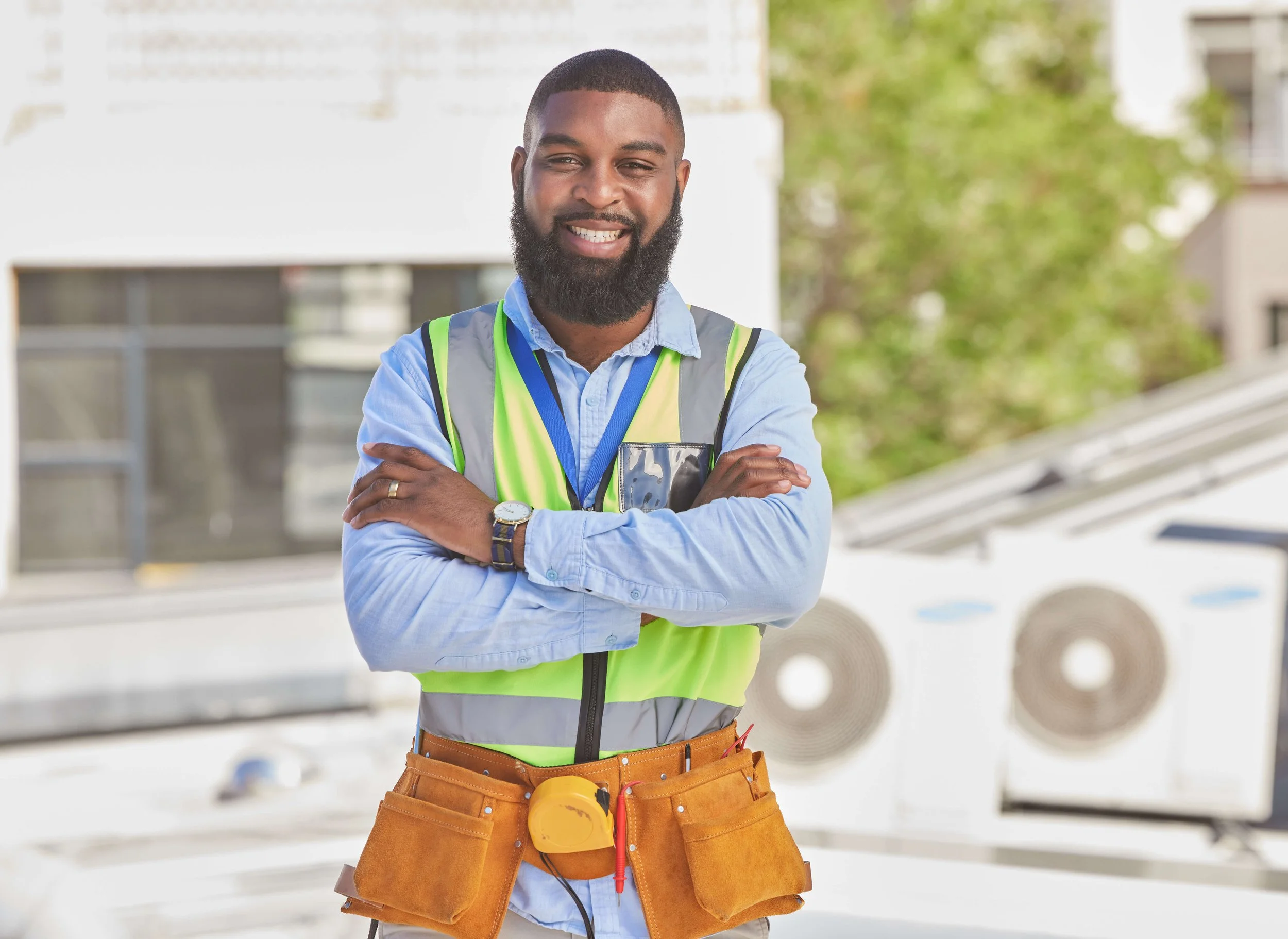 Smiling HVAC contractor in safety vest and tool belt promoting skilled and trained professionals for California schools, municipalities, and facilities.