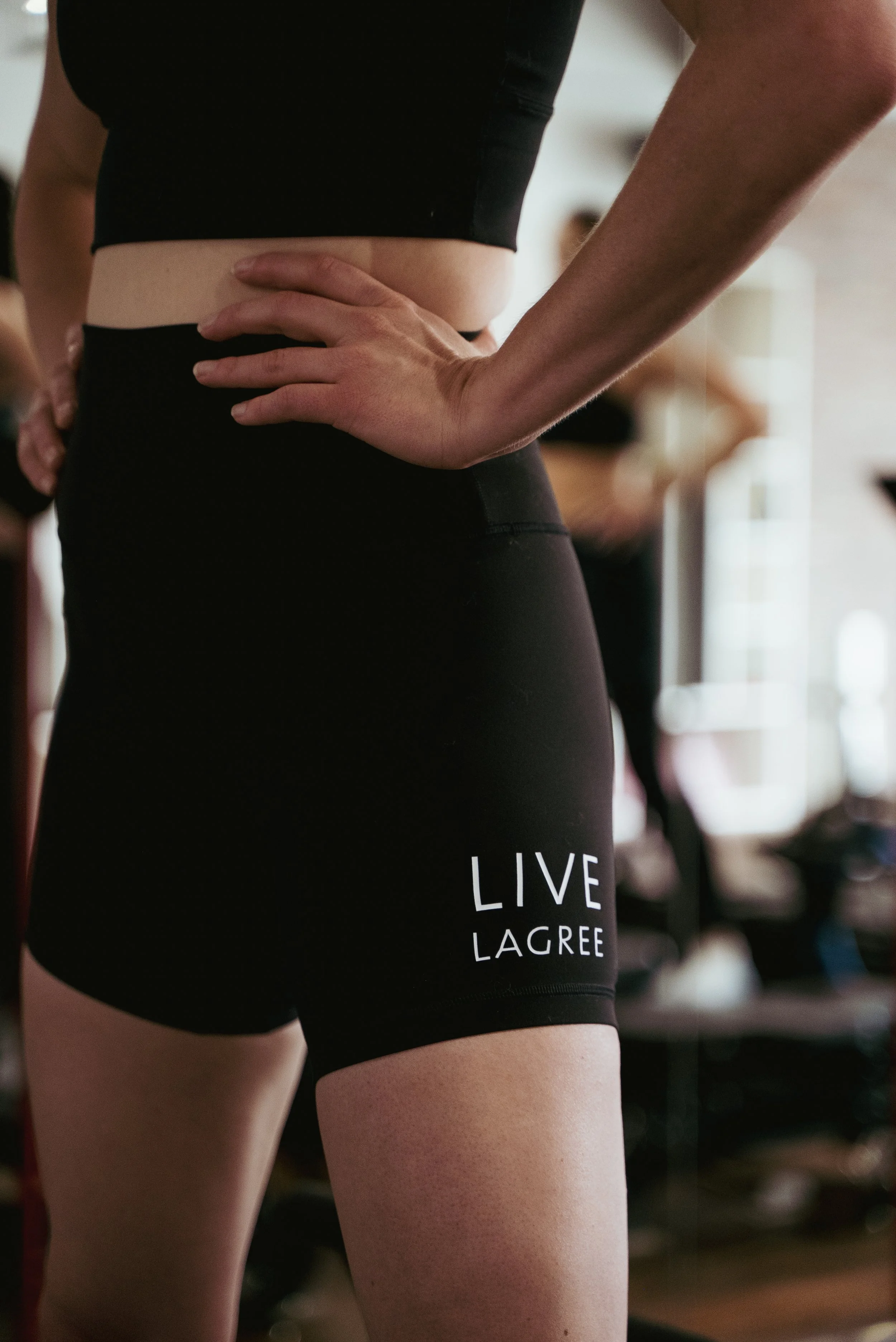 photo of a woman on a machine wearing black shorts with the words LIVE LAGREE on them.