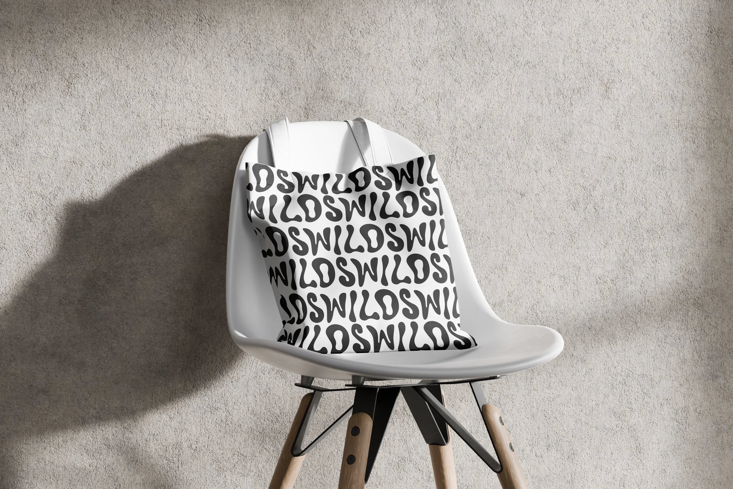 White modern chair with wooden legs, a black metal support, and a black and white tote bag hanging on its back, placed against a beige textured wall. brand design.