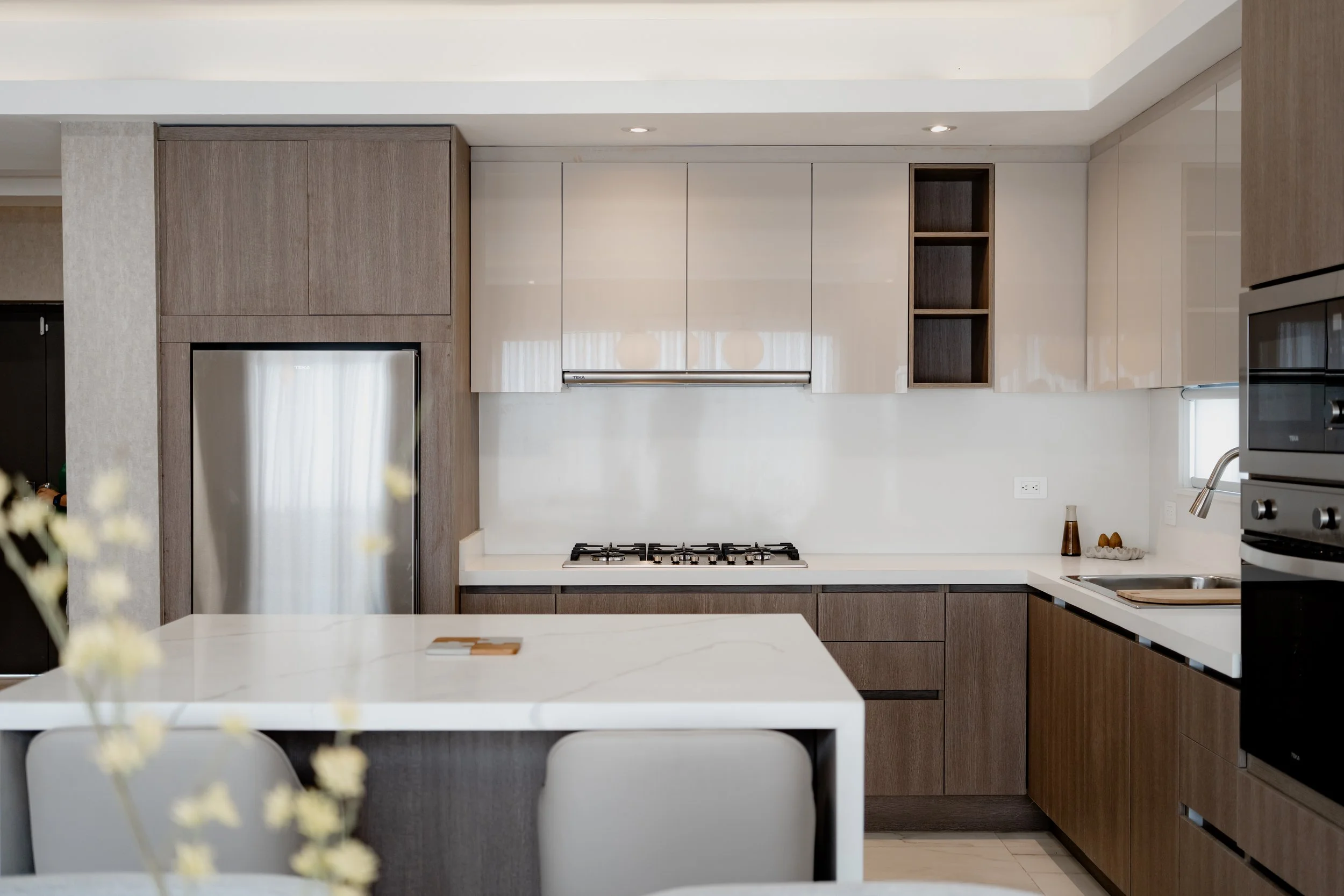 Modern kitchen with white countertop, wooden cabinetry, and stainless steel appliances. interiors photography