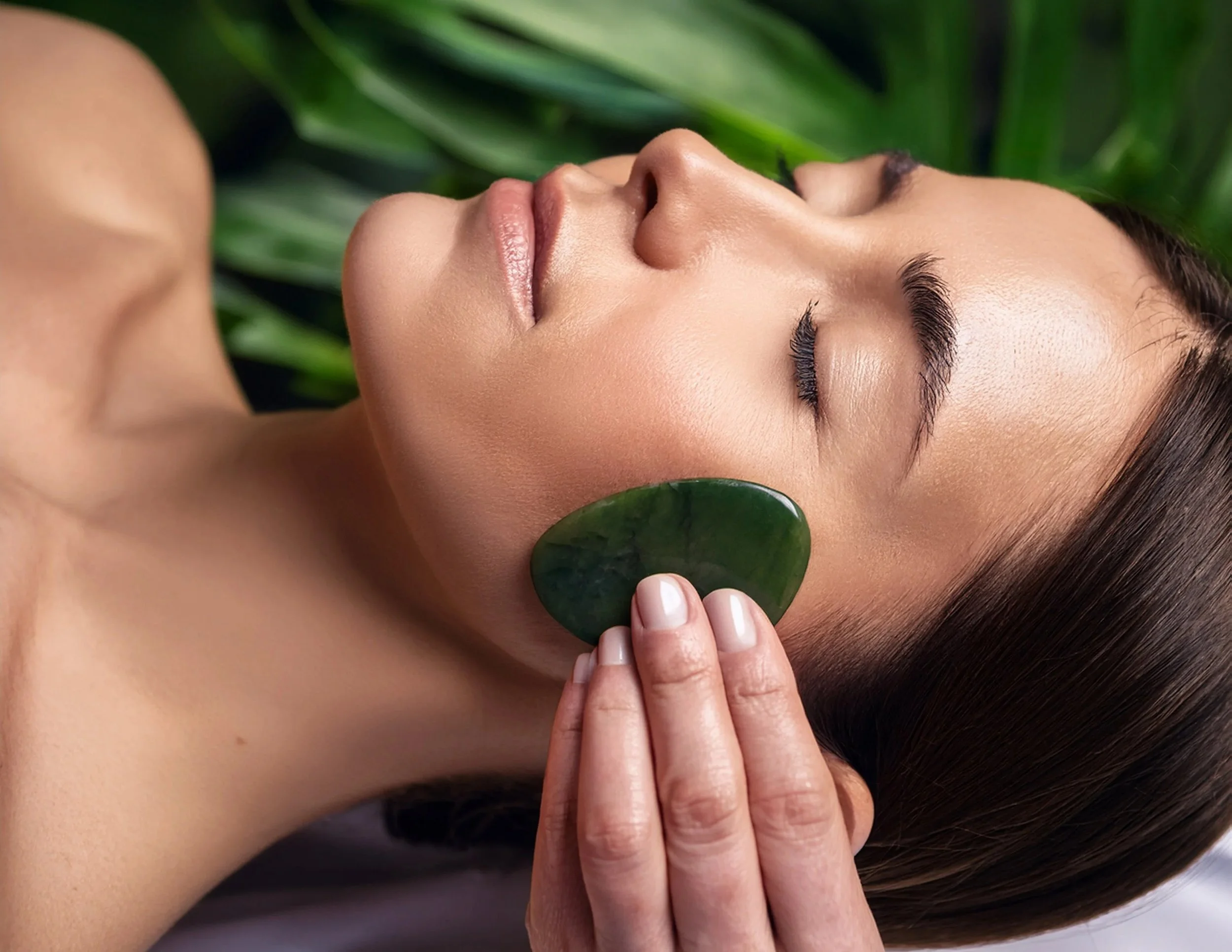 Acupuncturist treating face with jade gua sha tool