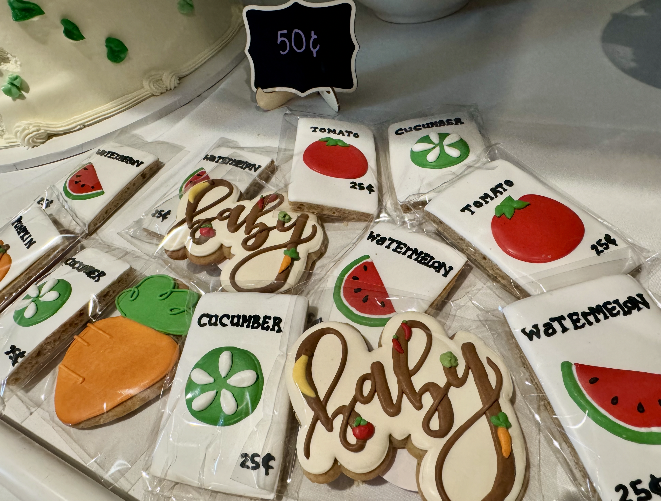 Cookies decorated with images of a tomato, cucumber, watermelon, and green flower, with labels and prices.