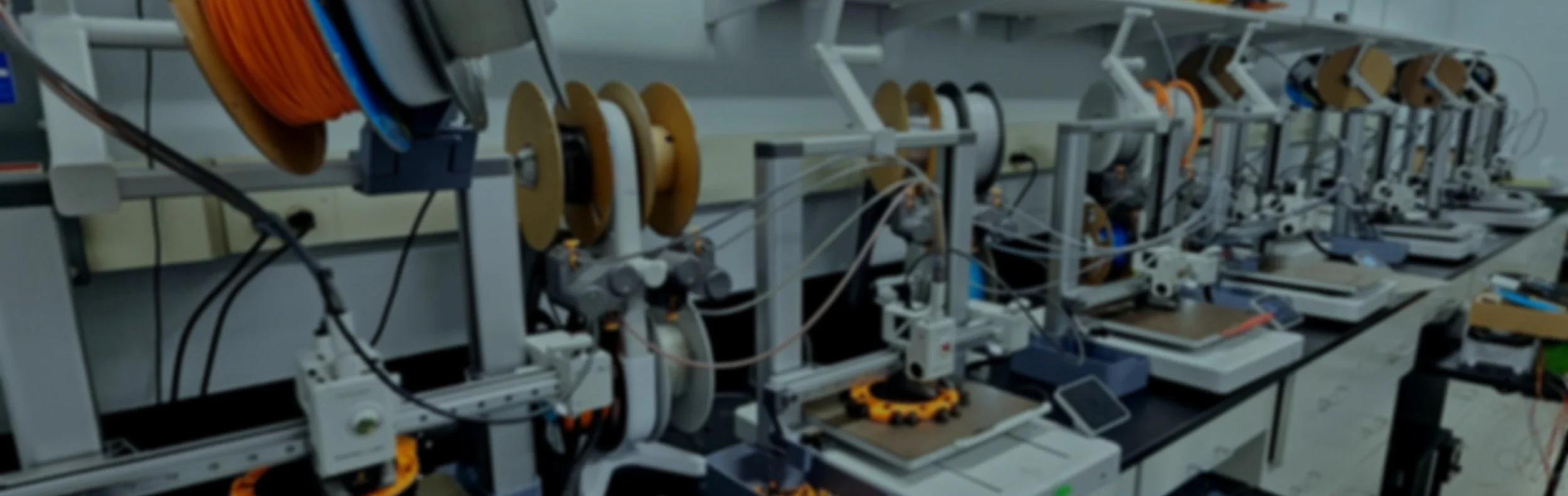 Row of scientific laboratory equipment with spools of wire and electronic components on workbenches.