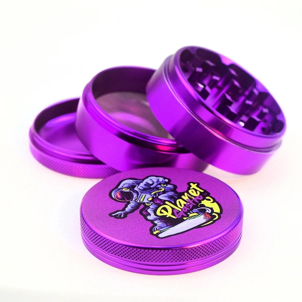A purple metal grinder with three sections, one with a cartoon astronaut and the words 'Planet Blast' on the lid, designed for grinding herbs or spices.