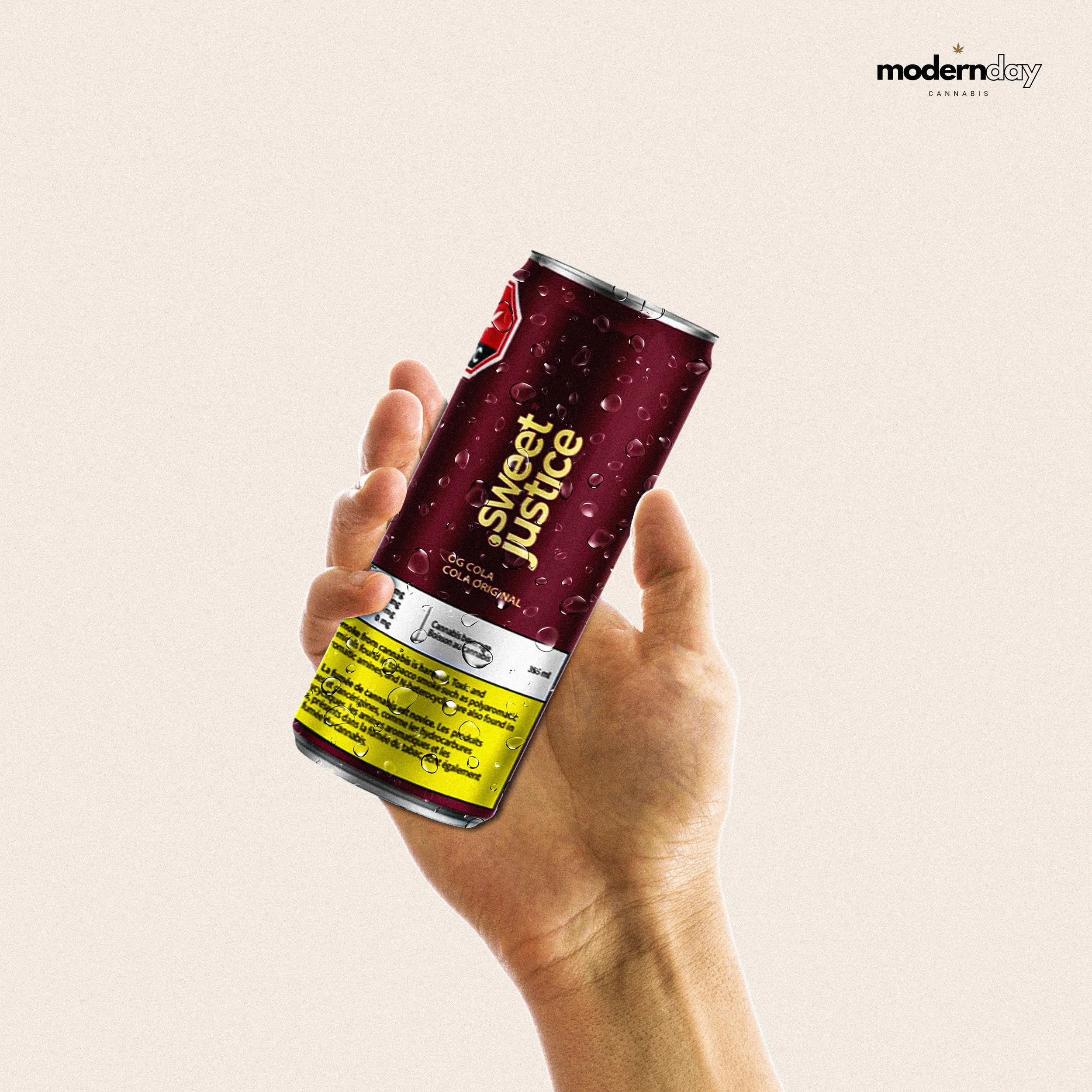 A hand holding a red can of Sweet Justice soda with water droplets on it, against a plain light background, with the Modern Day Cannabis logo in the top right corner.