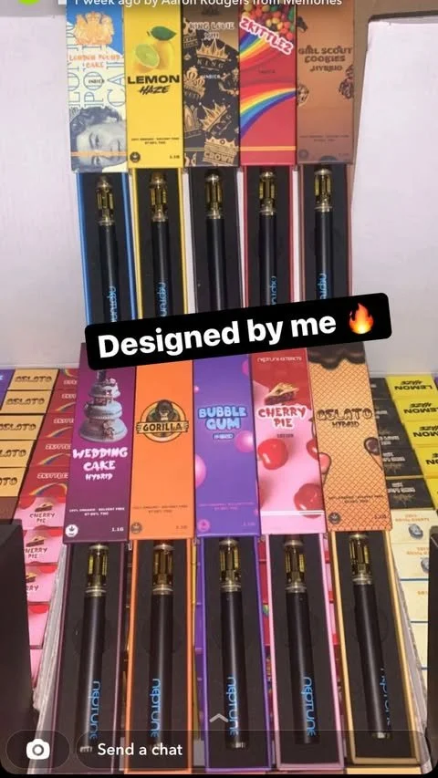 Display of electronic cigarette vape pens in colorful packaging with a sticker that says "Designed by me" and flames icon.