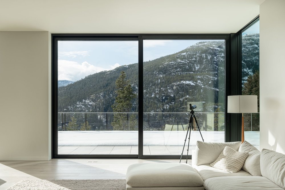 Living room with a low sectional, sliding glass to the terrace and the ridge beyond