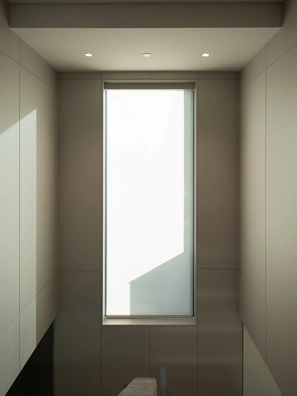 Tall slot window above a stair, pale panelled walls and a diagonal of light