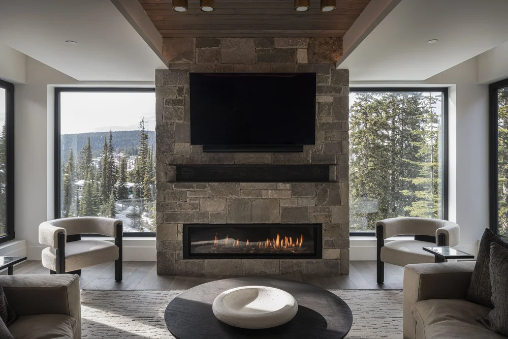 Lounge with a screen above a long fireplace set in stone, two armchairs facing