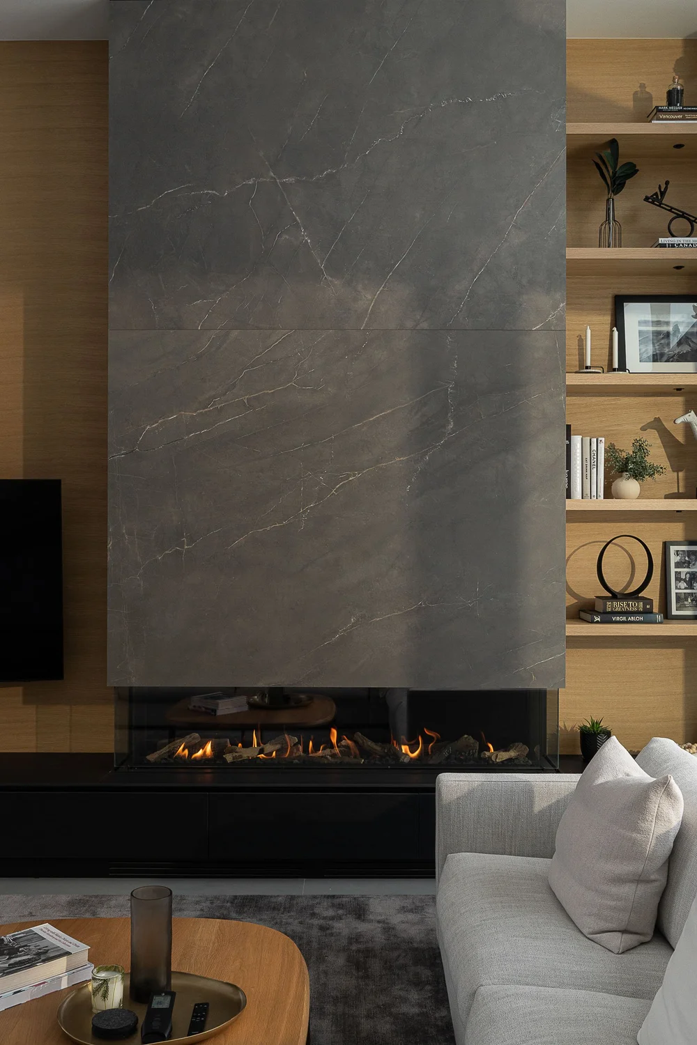 Fire lit in a long firebox below a full height stone slab, shelving alongside