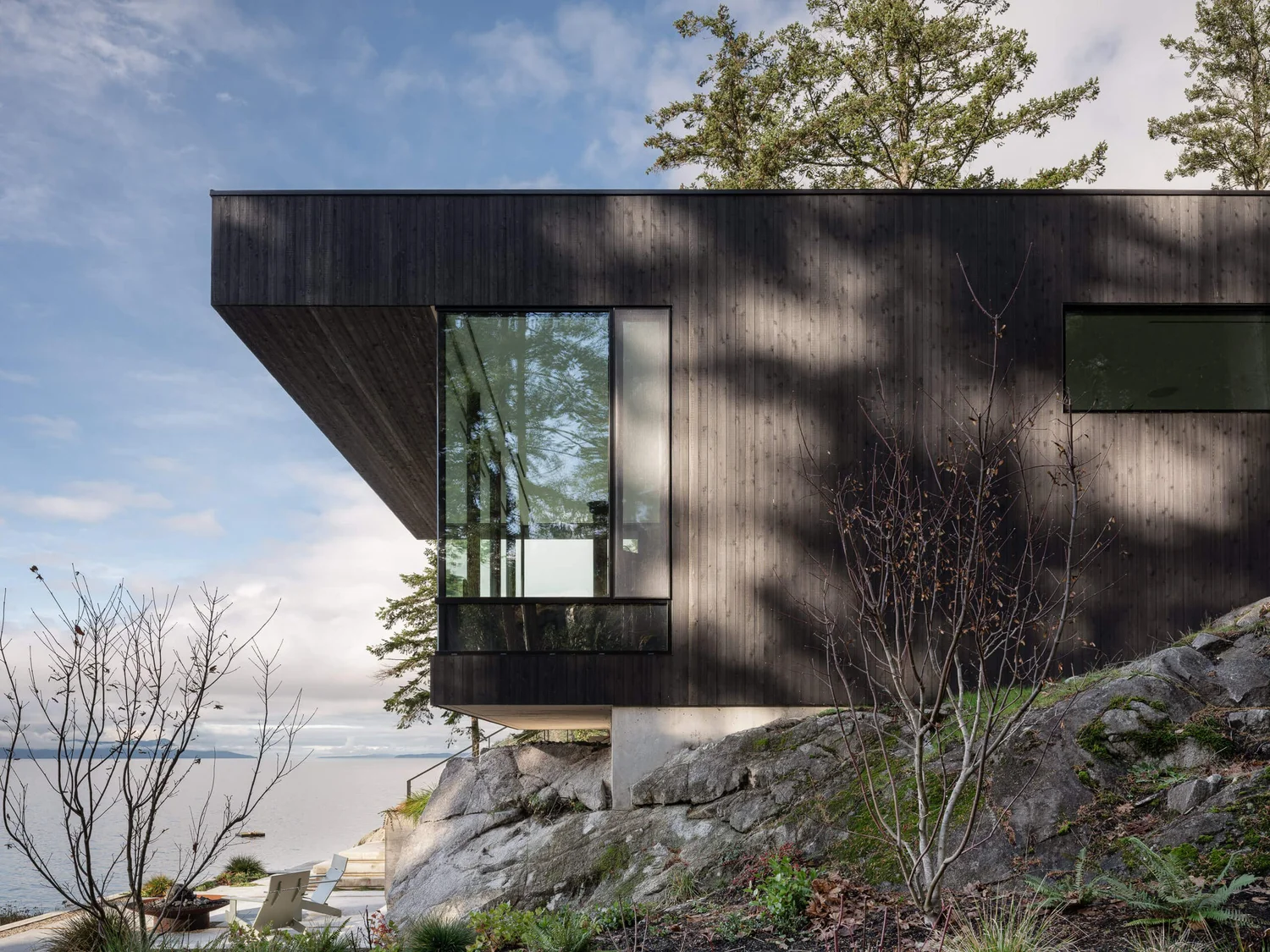 A dark clad corner projecting out over rock, the sea and low cloud beyond