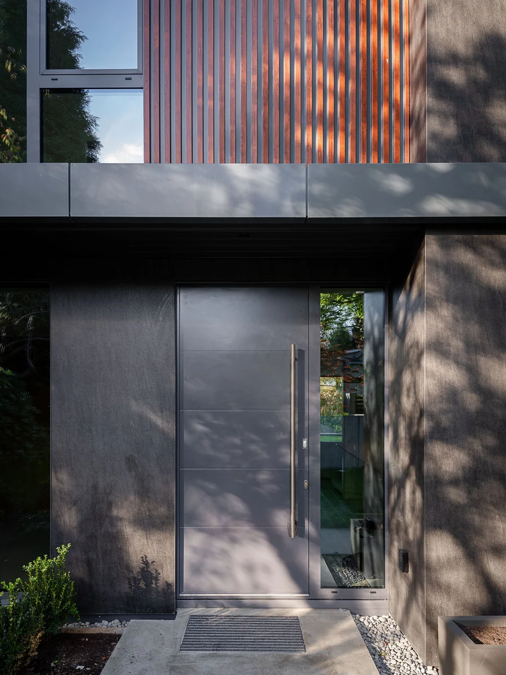 The entry door below a screen of vertical wood slats, shadow moving over both