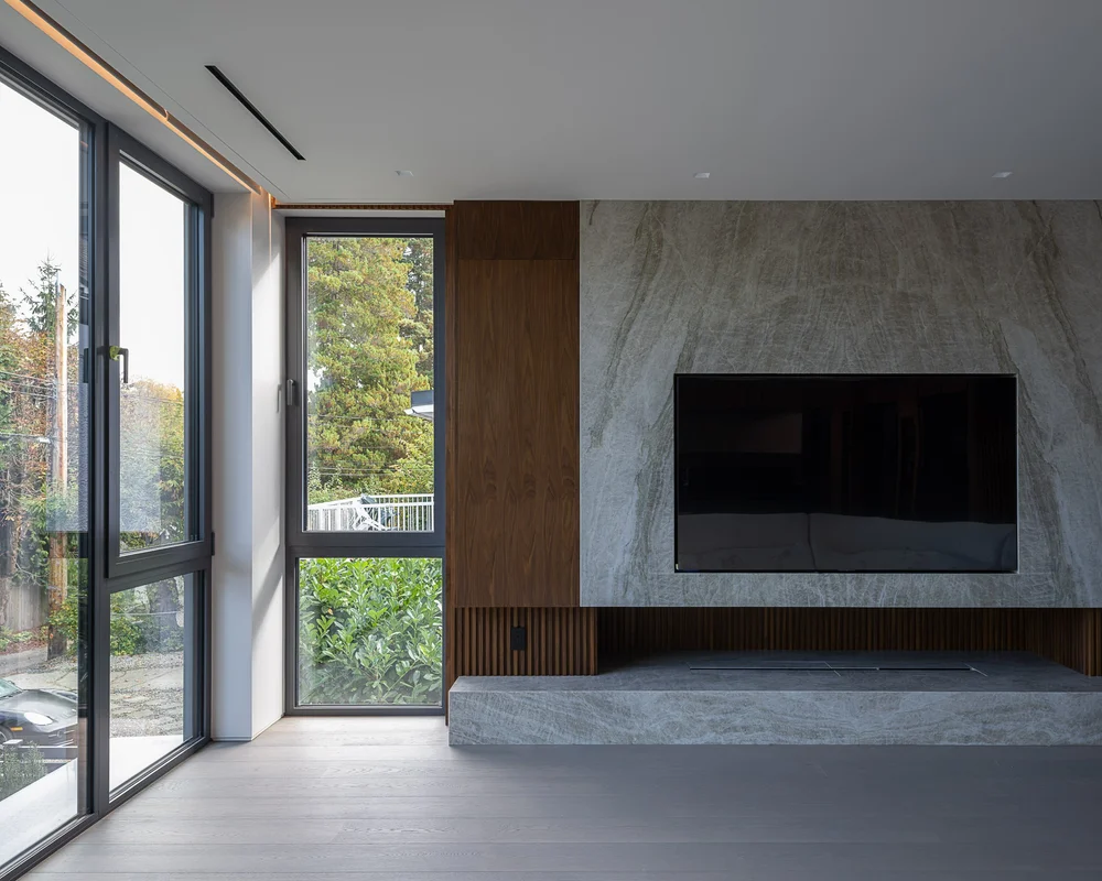 The stone fireplace wall from the side, a timber panel beside it and glazing at left