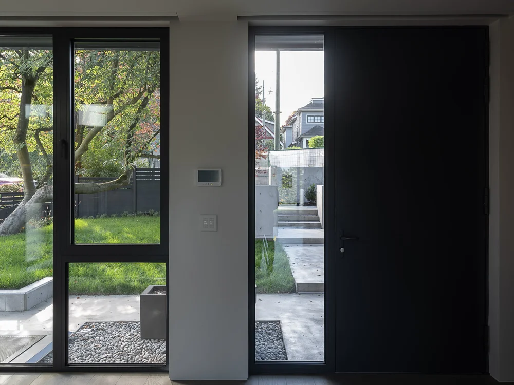 The front door standing open beside its full height sidelight, lawn and steps beyond