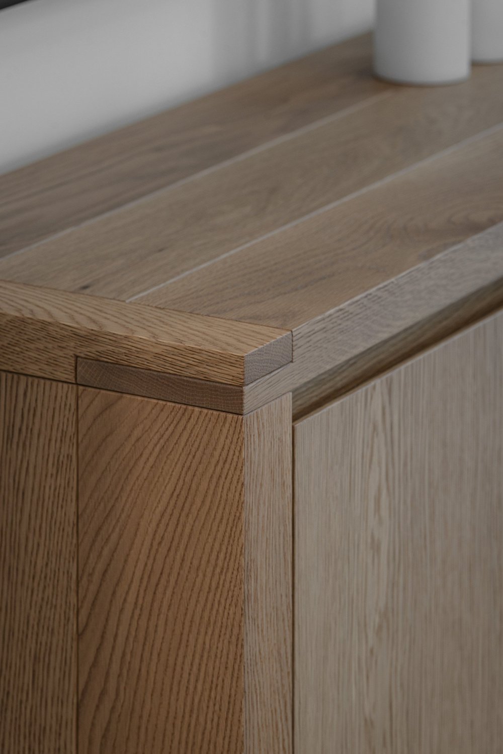 Mitred timber corner meeting a pale stone top, the grain running around the edge