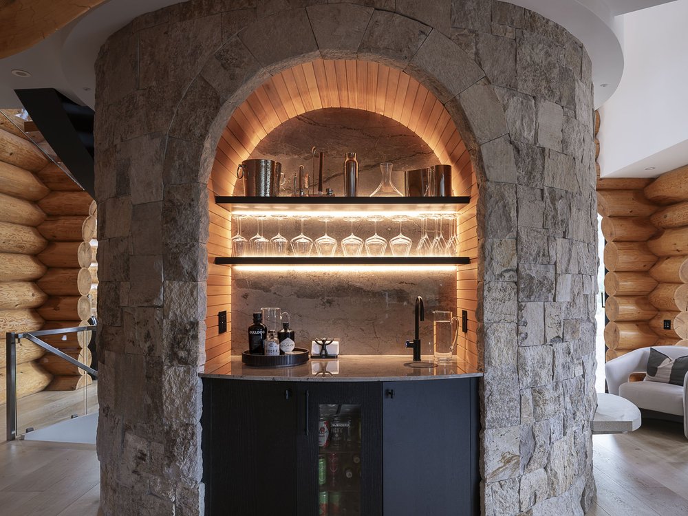 Bar set into an arched alcove in a stone wall, lit shelves of glassware above