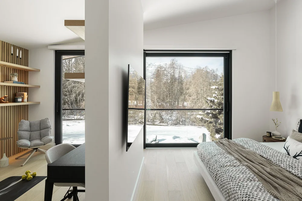 Bedroom beside a window onto snowy trees, the exercise room through an opening beyond