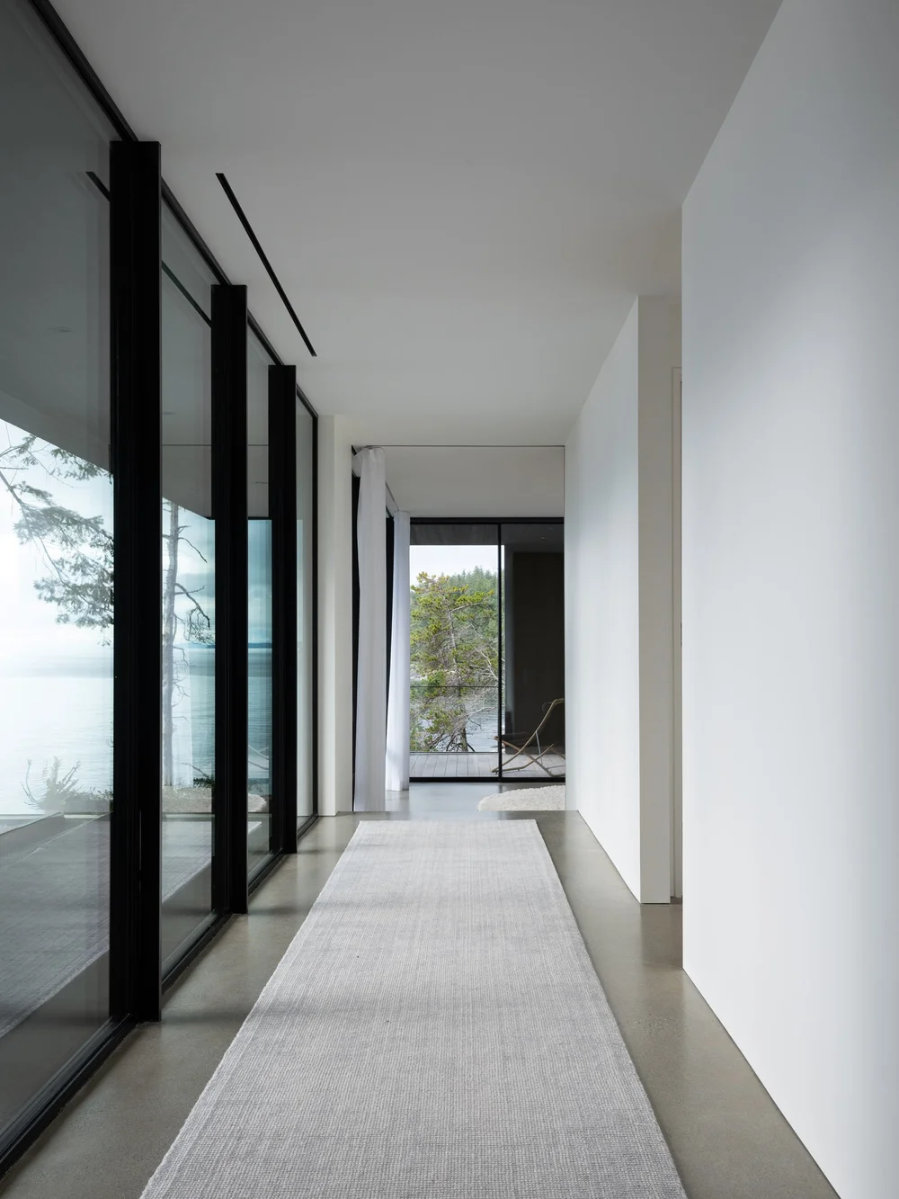 Corridor along full height glazing, a pale runner laid on the polished concrete floor