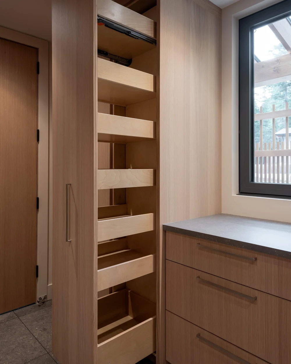 Tall pull out pantry units standing open beside a run of wood cabinetry
