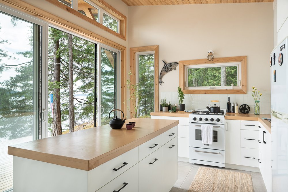 The kitchen island in the foreground, sliding glass open to trees and the water